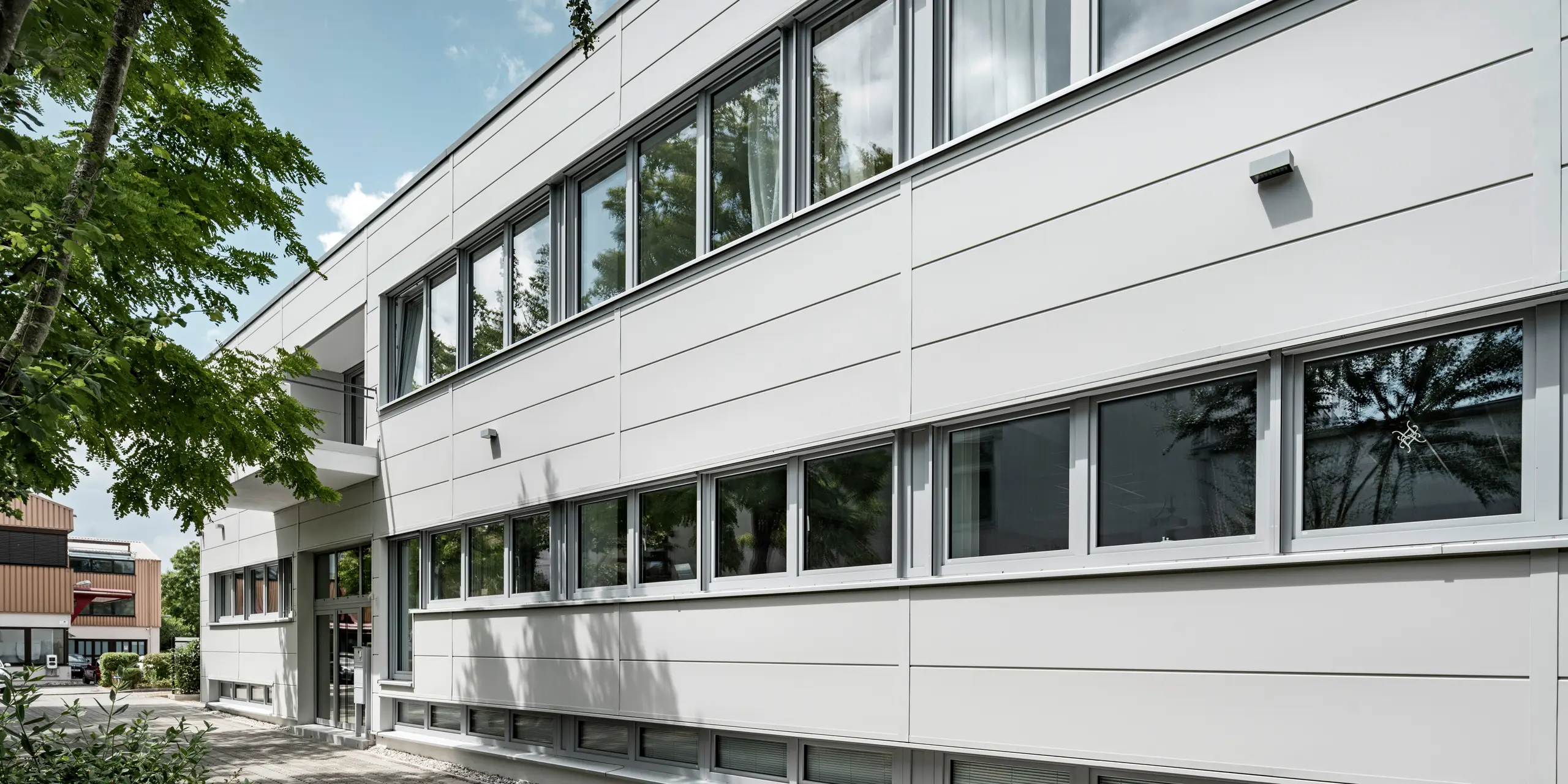 Großformatige PREFA Sidings umhüllen ein Firmengebäude in Oberschleißheim (Deutschland). Die extrabreiten Fassadenelemente aus Aluminium sind in der Farbe Prefaweiß gehalten.