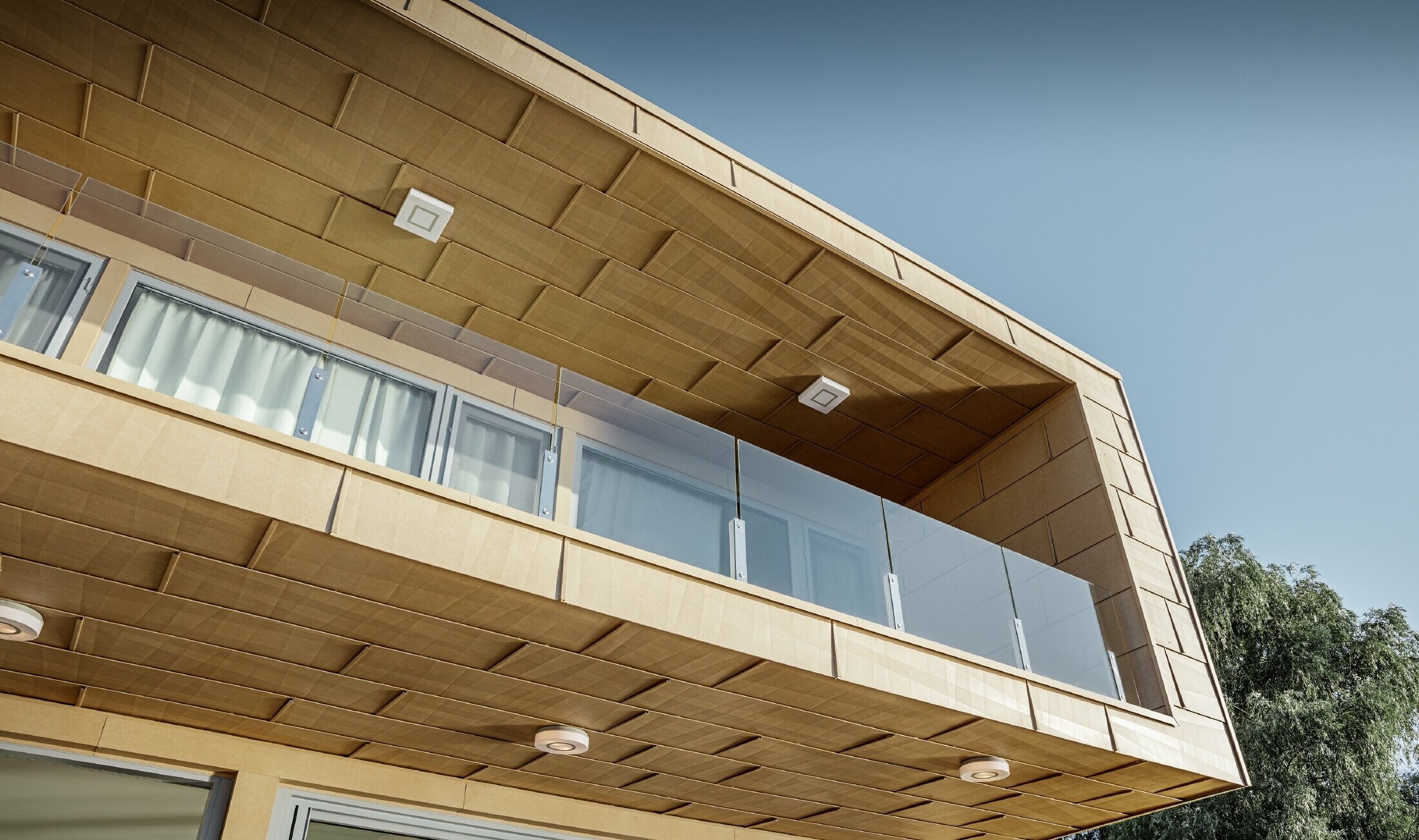 Modern lakeside weekend residence with a flat roof, large windows and a canted aluminium façade in sand brown