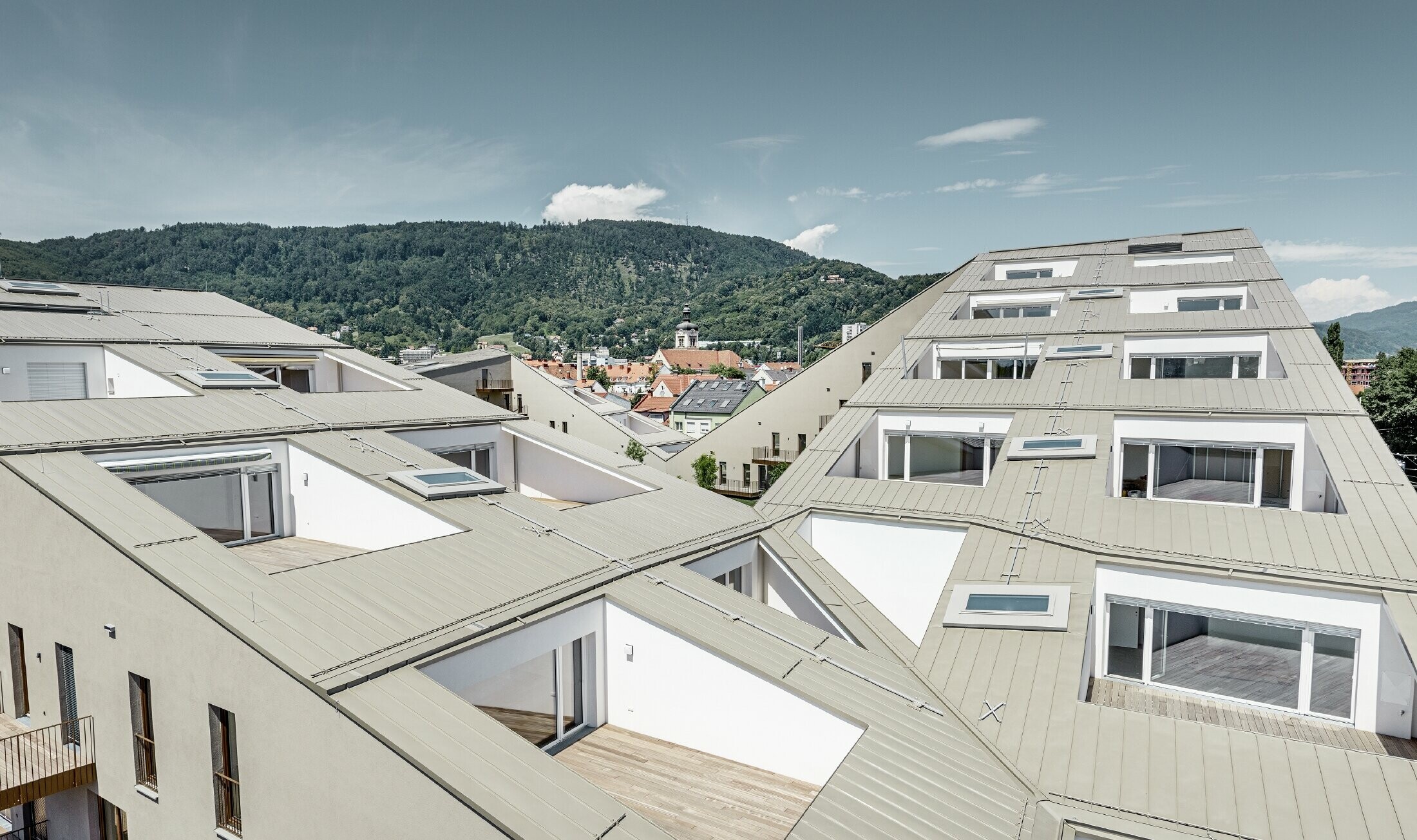 Extended residential complex with a flat roof surface and integrated terraces, generous windows and a Prefalz roof in the special colour of metallic bronze