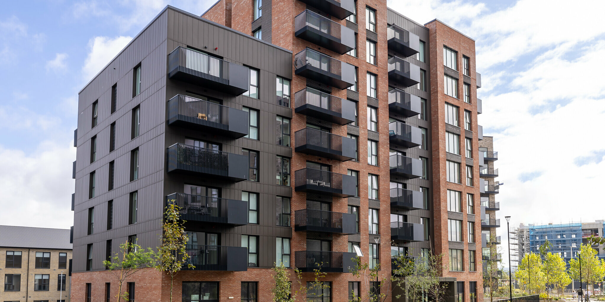 Front view of the Citywest Apartments in Dublin. Combination of traditional brick façade and 700 m² PREFA sidings made of high-quality sheet metal in the colour P.10 brown. The aluminium panels give the residential building a modern, urban appearance with high weather resistance.