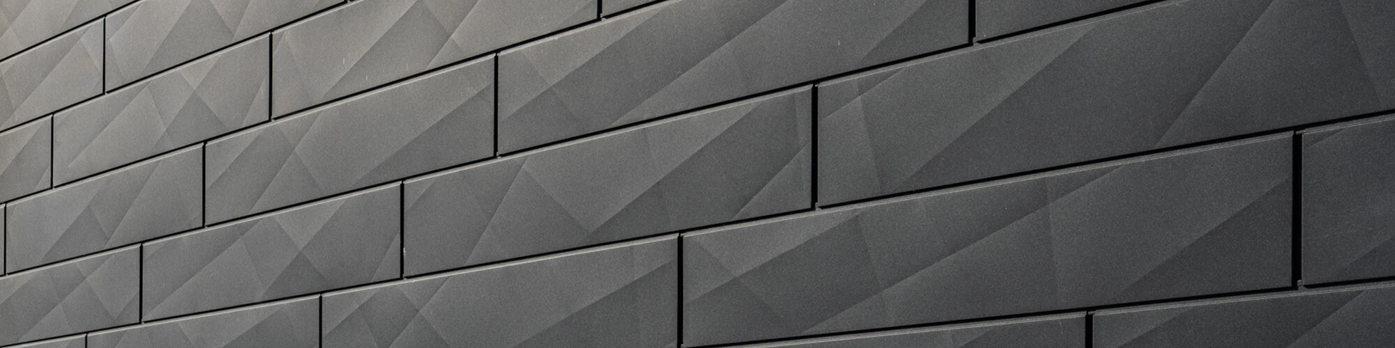 The anthracite-coloured façade made of irregularly structured siding.X panels up close.