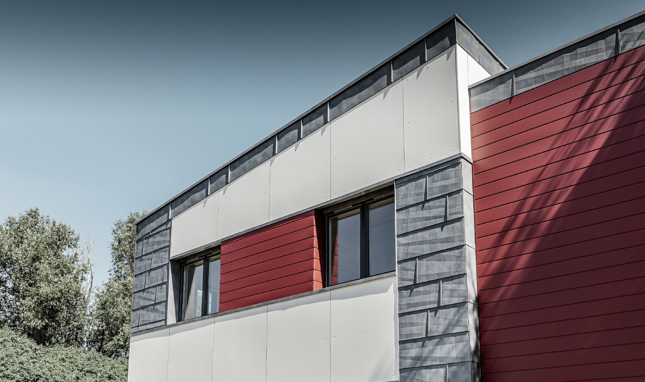 Modern office building with a divided façade in red, stone grey and white, and sidings, FX.12 façade panels and aluminium composite panels made by PREFA Aluminiumprodukte GmbH