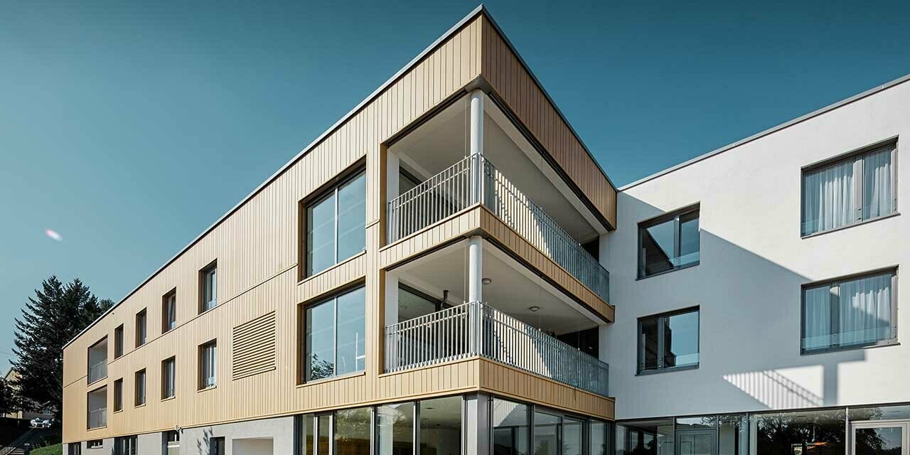 Retirement home with a flat roof and a sand brown siding façade made by PREFA