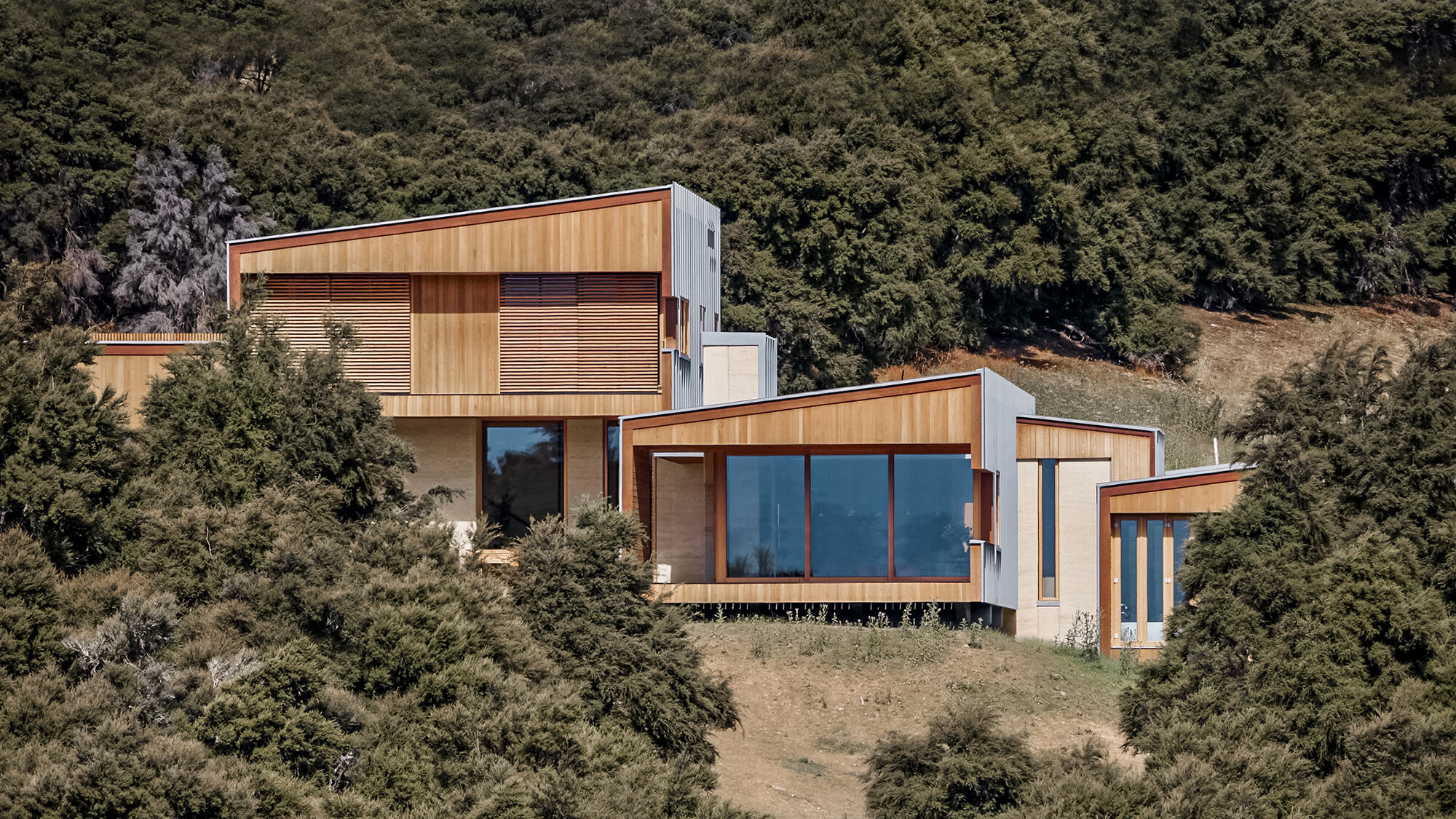 The house, framed by the bush forest, with its protruding storeys from a normal perspective.