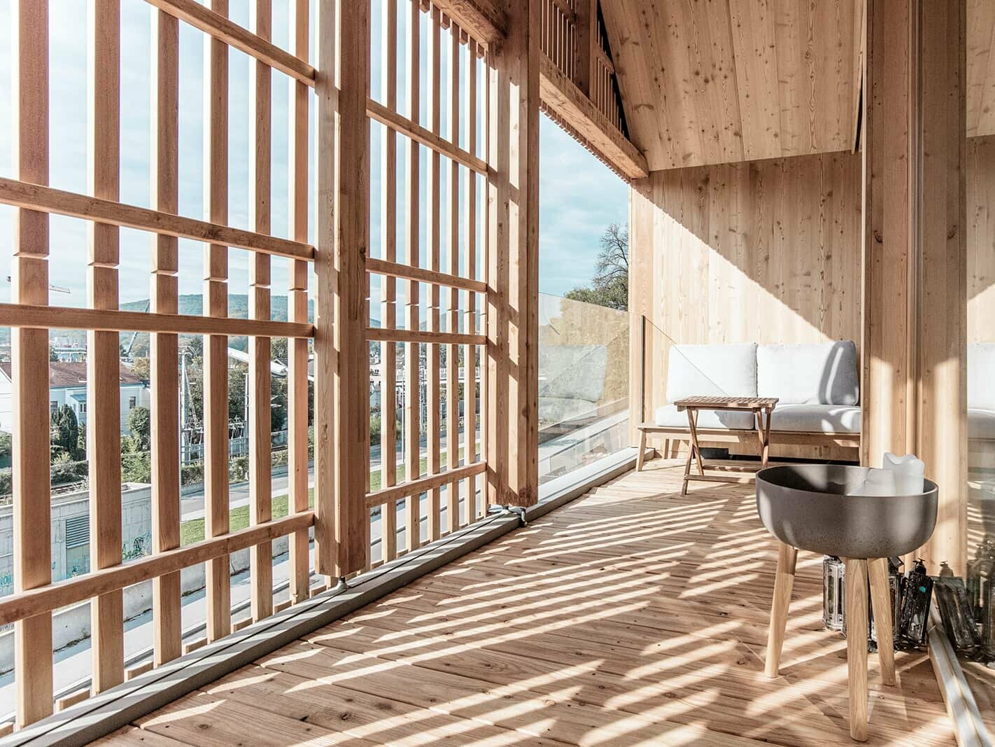 Interior view of the detached house in Vienna, Austria. Inside, the used wood is reflected. A little table and couch are illuminated by the sun, the wooden slats casts striped shadows.