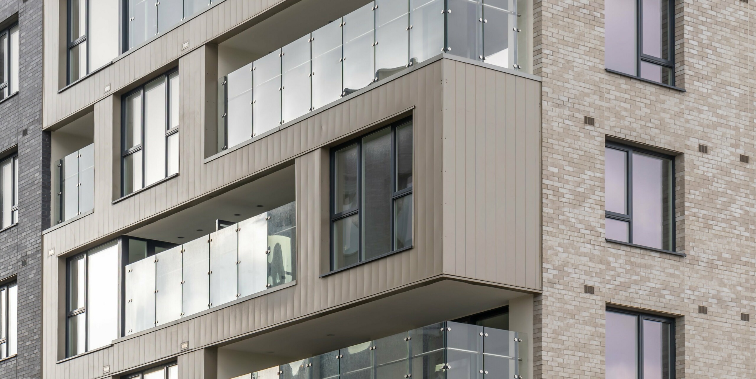 Apartment block in the Palmers Gate housing estate in Palmerstown, Dublin, Ireland. The façade of the building is clad with bronze-coloured PREFA Sidings and brick elements. Balconies with glass balustrades extend over several storeys and offer the residents modern and secure outdoor spaces. A total of approx. 1,700 m² of PREFA sidings and approx. 1,200 m² of PREFALZ façade system were used, which impress with their robustness and aesthetic design. The combination of high-quality sheet metal and bricks creates a harmonious and elegant appearance.