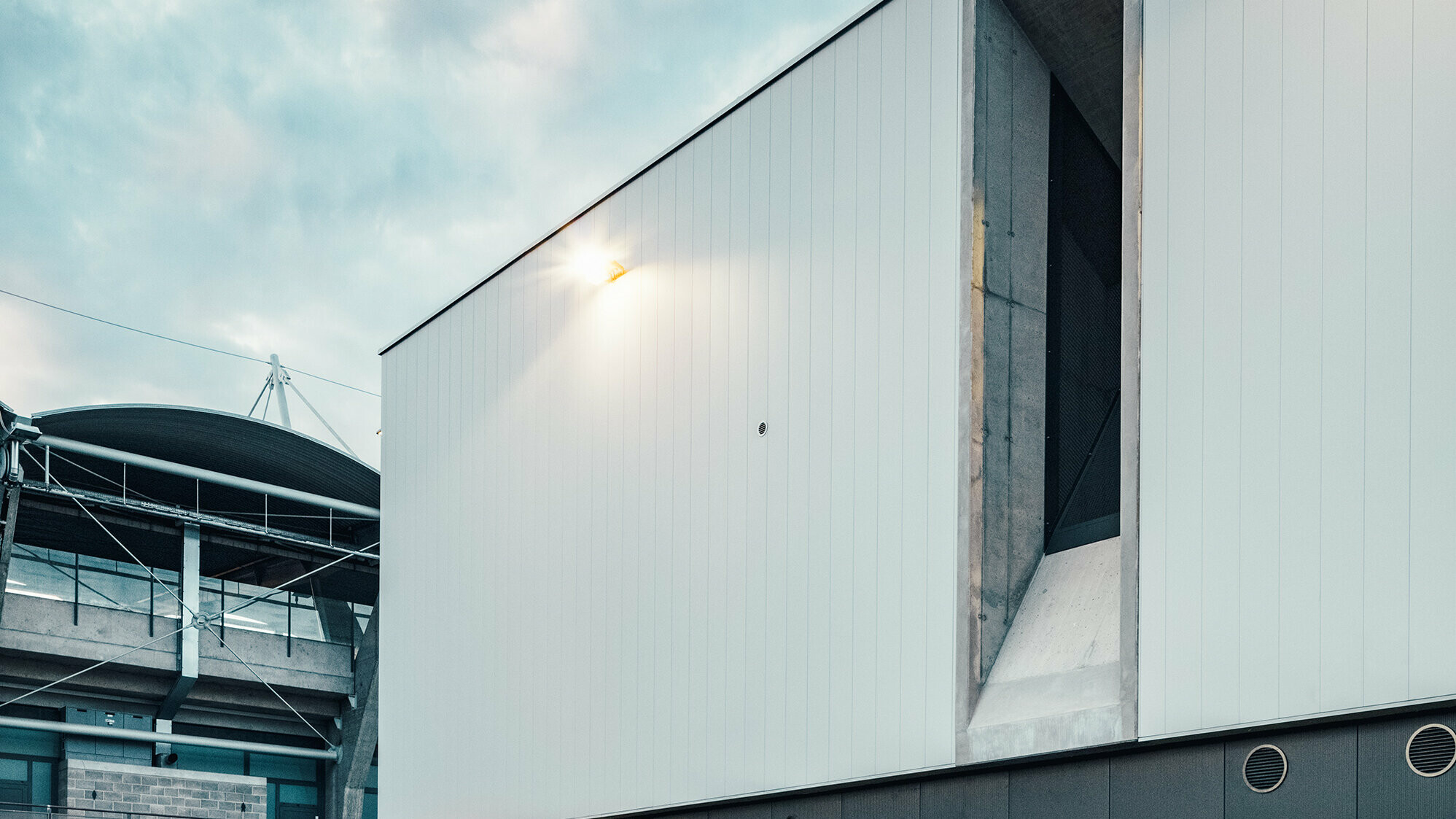 Close-up of the side wall with the ventilation shaft. In the background: the football stadium.