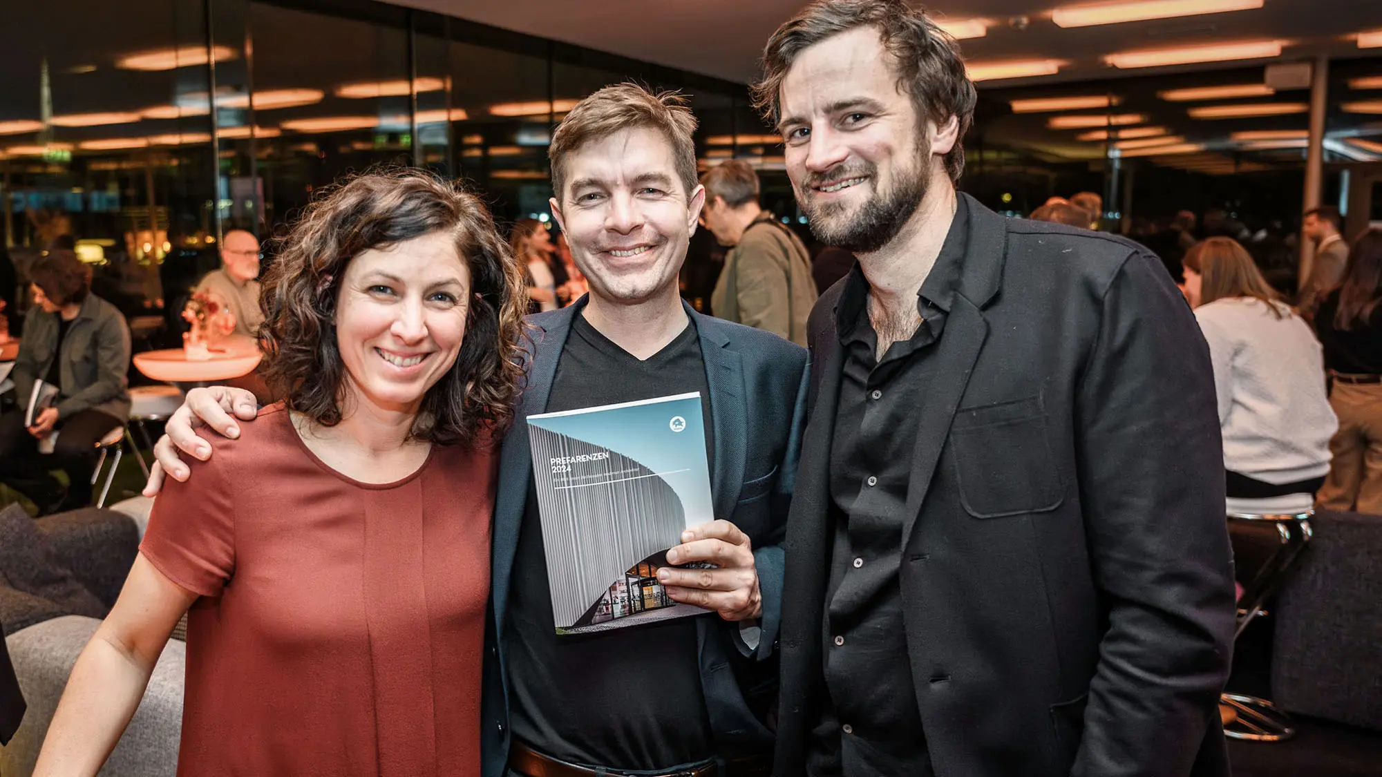 Architect Susi Matt, architect Mario Dallaserra, holding the PREFARENZEN book 2024 in his hand, and architect Benedikt Hörmann.