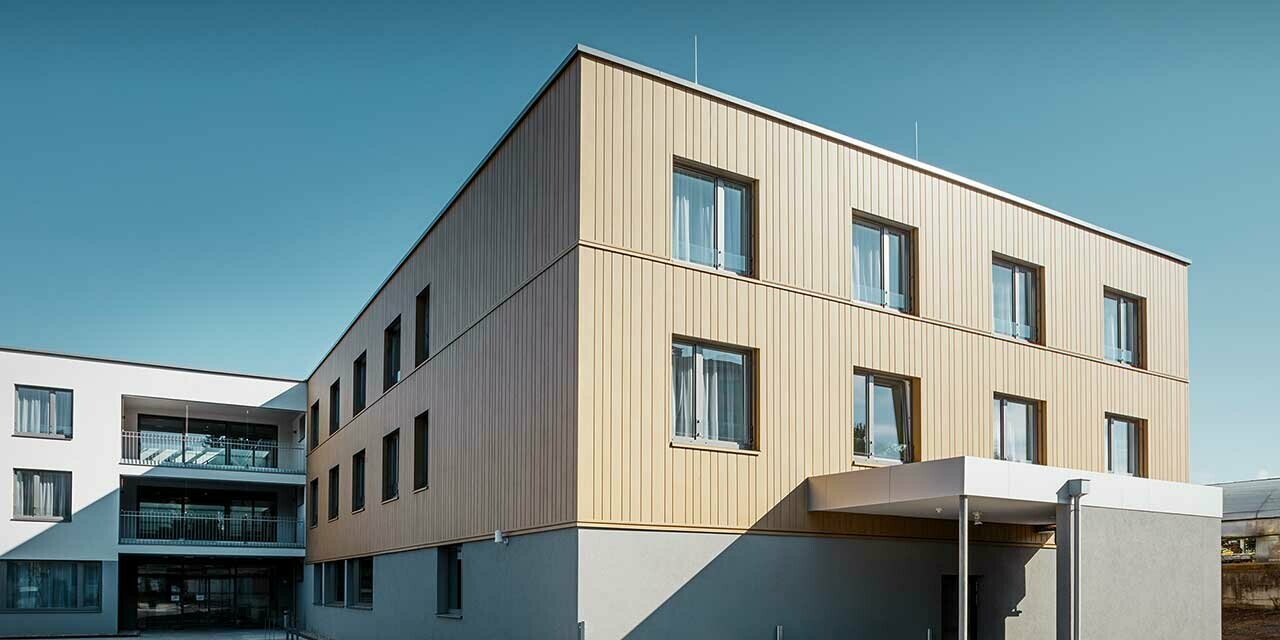 Retirement home with a flat roof and a sand brown siding façade made by PREFA