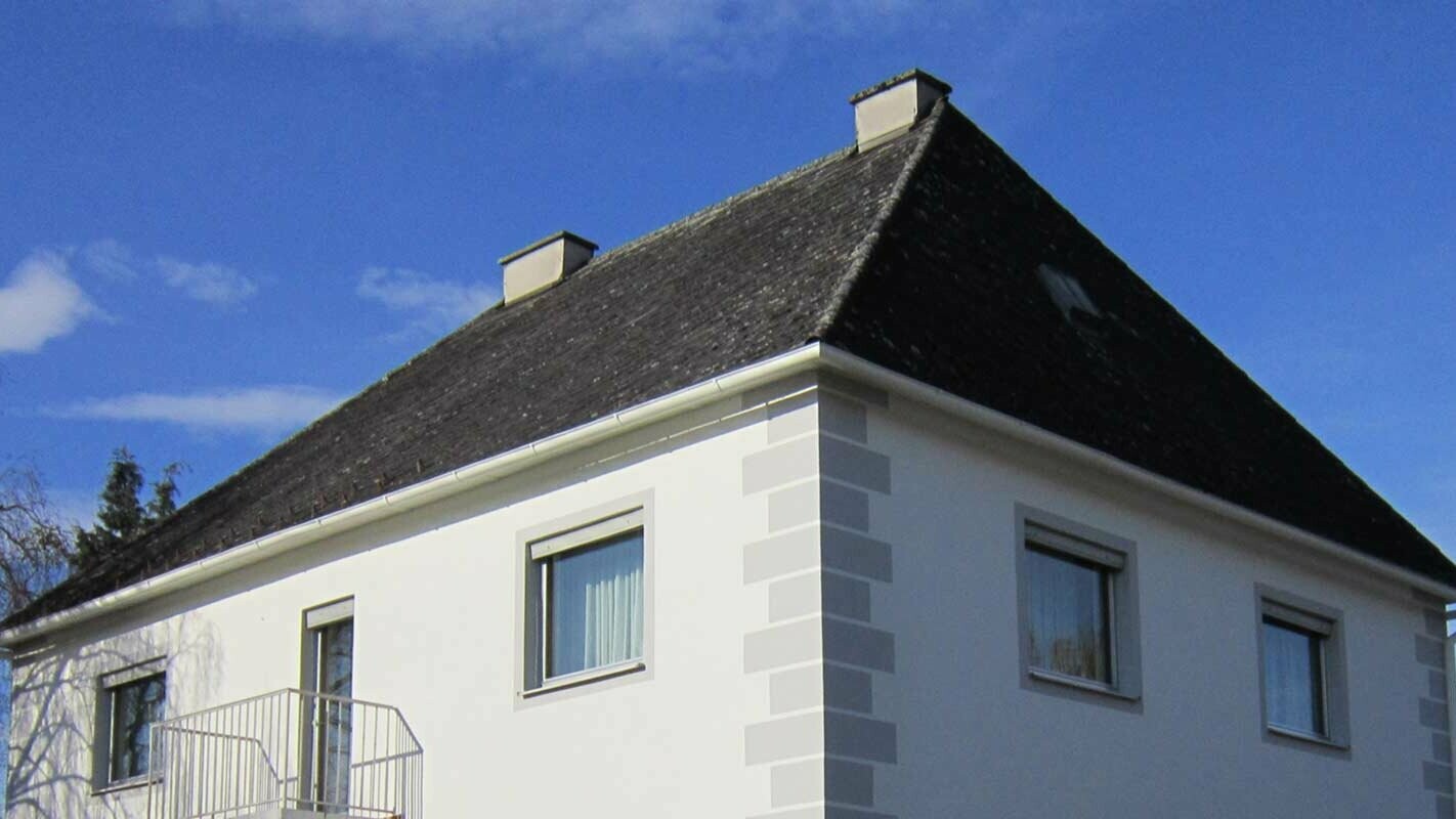 House with a hipped roof before roof renovation with Prefalz and PREFA roof tiles in Austria