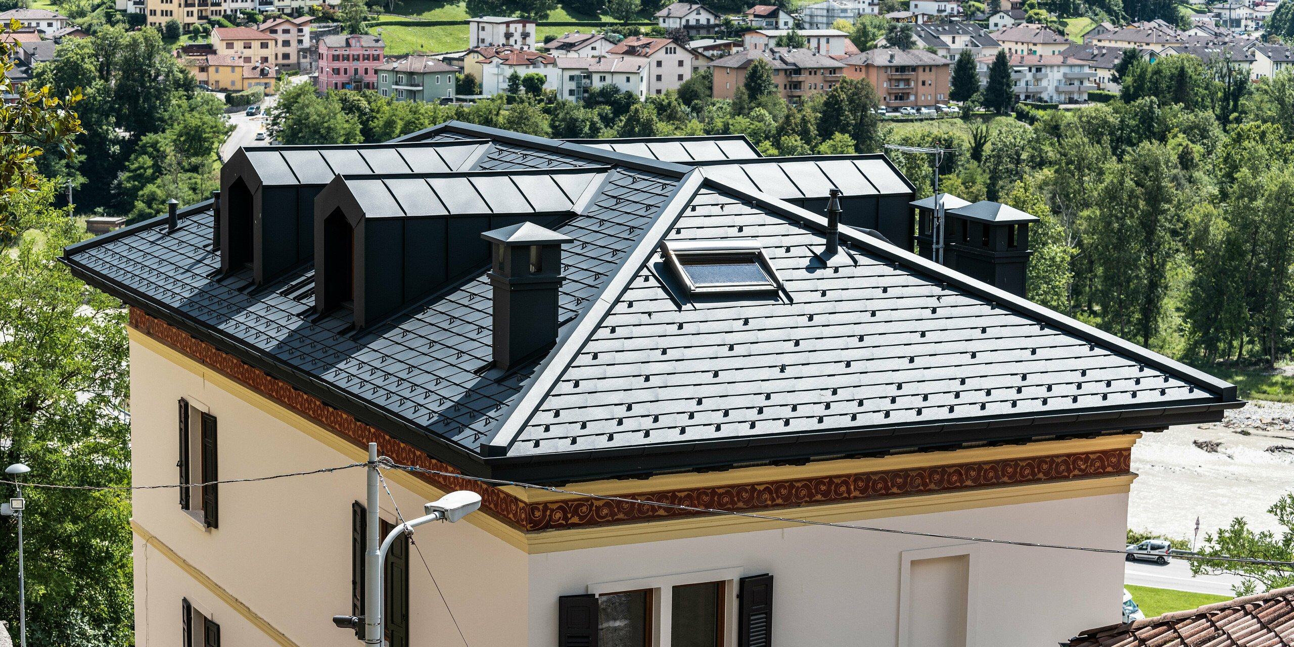 Historisches Wohngebäude in Belluno, Italien, sorgfältig saniert unter Beachtung des Denkmalschutzes. Das Dach wurde mit leichten, anthrazitfarbenen PREFA Dachschindeln aus Aluminium ausgestattet. Passend dazu wurden die Dachgauben und Kaminverkleidungen mit elegantem PREFALZ umhüllt, um das architektonische Erbe zu bewahren und gleichzeitig die Struktur zu schützen. Die Dachentwässerung von PREFA vervollständigt das ästhetische und funktionale Update, alles in der zeitlosen Farbe P.10 Anthrazit.