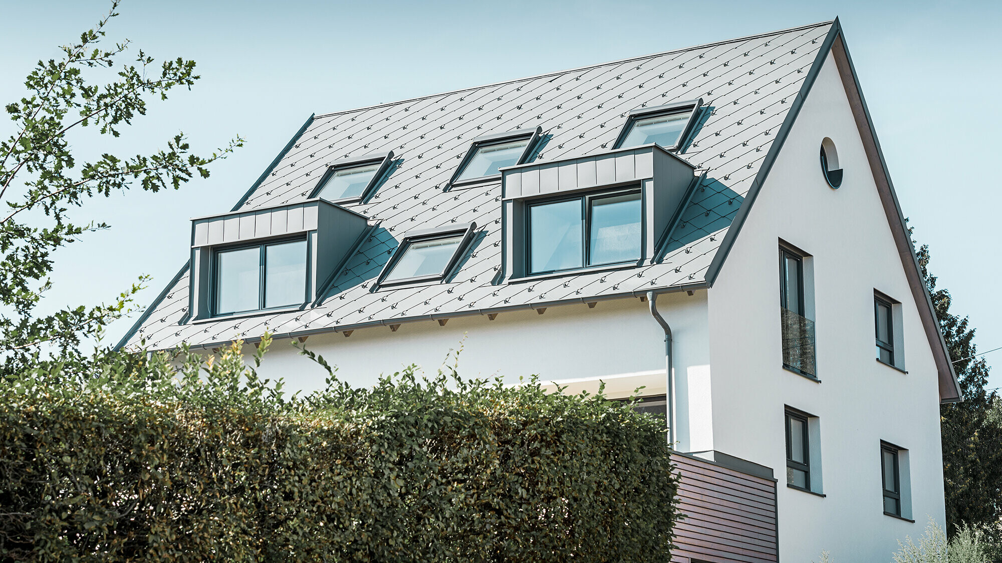 Roof refurbishment of a gabled roof with two dormers and four roof windows. The roof was covered with PREFA light grey 44 × 44 rhomboid roof tiles. The PREFA hanging gutter, also in light grey, was used for the guttering. 