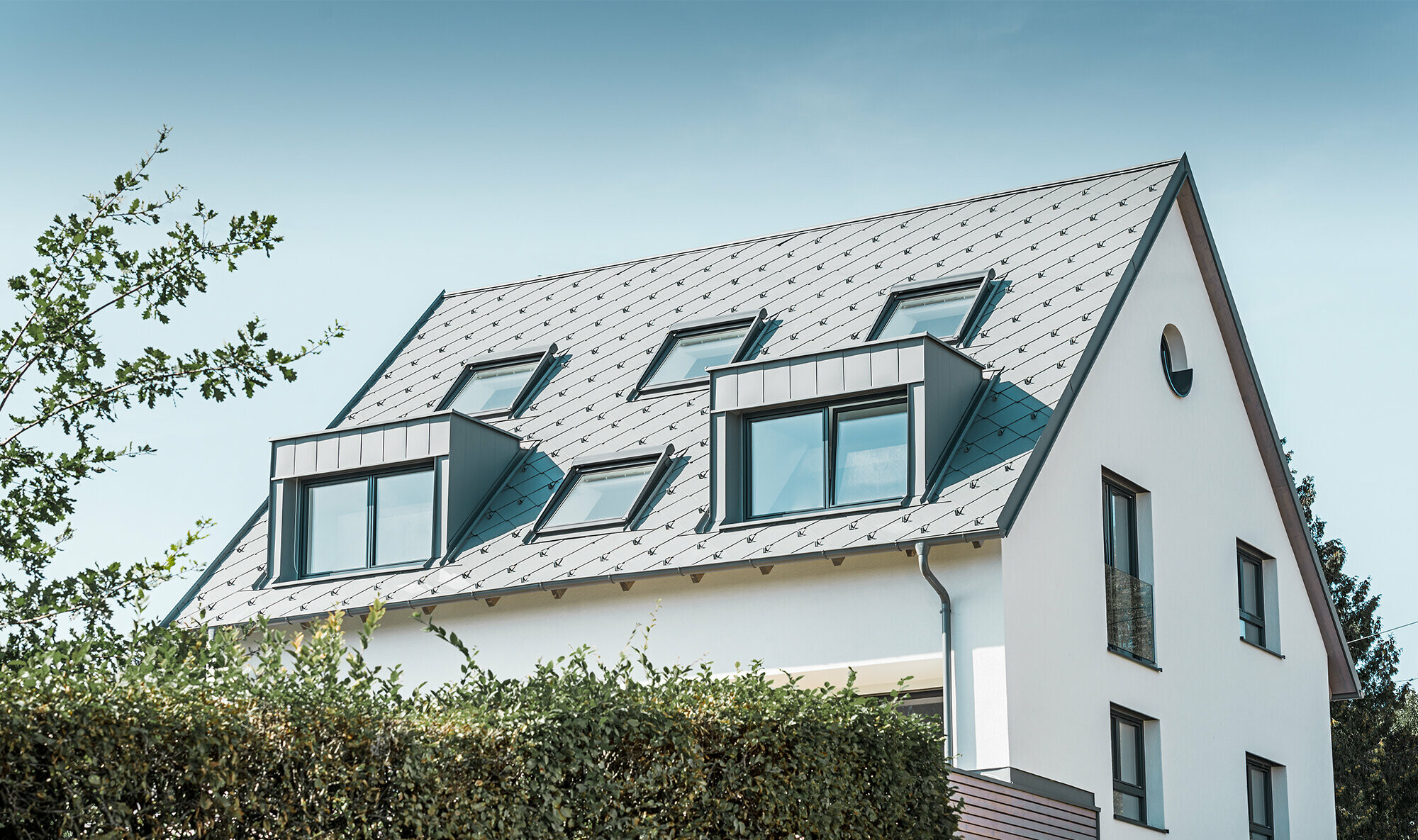 Roof refurbishment of a gabled roof with two dormers and four roof windows. The roof was covered with PREFA light grey 44 × 44 rhomboid roof tiles. The PREFA hanging gutter, also in light grey, was used for the guttering. 