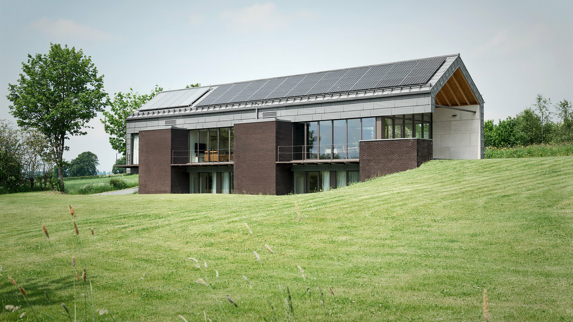View of the elongated structure from the southern garden side and of the harmonious interplay between brick and the PREFA aluminium panels.