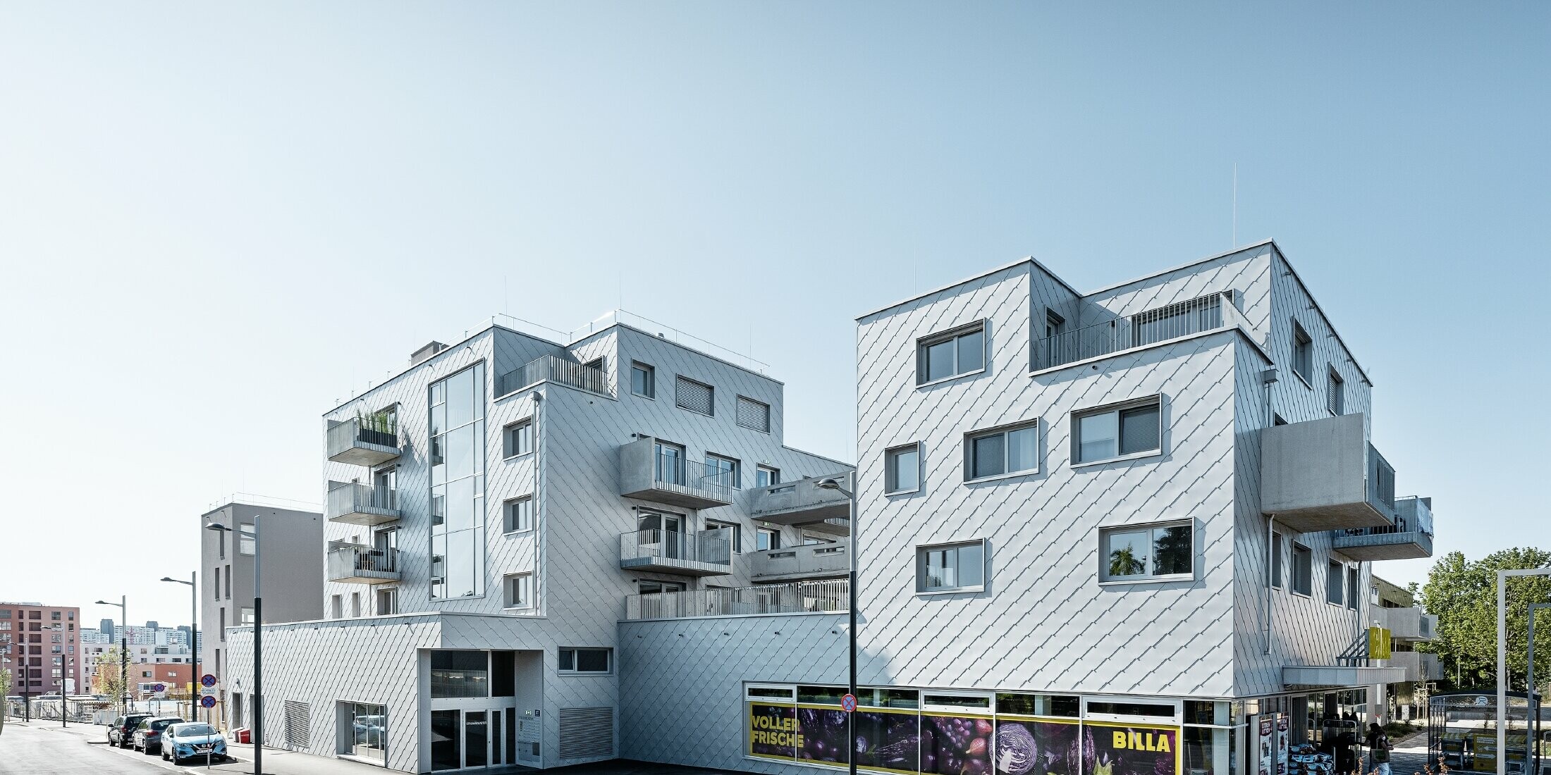 Apartment complexes with flat roof and rhomboid cladding on the façade with PREFA 44 × 44 rhomboid façade tiles in metallic silver