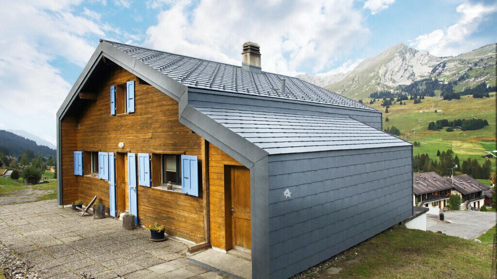 House in the Swiss mountains with a wooden façade combined with the PREFA rhomboid roof and façade tiles in stone grey