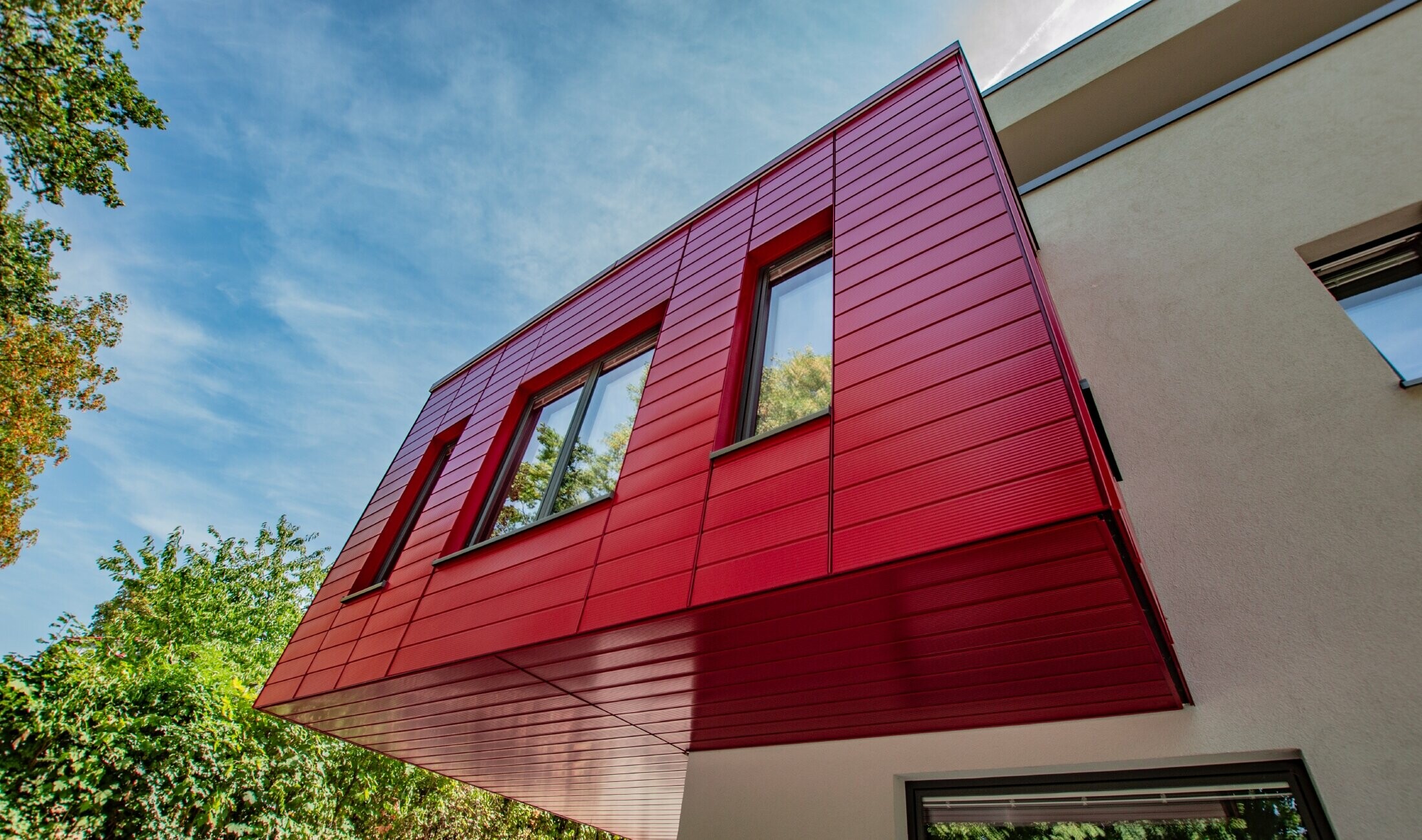 Bay window lined with horizontally installed PREFA sidings in ruby red.