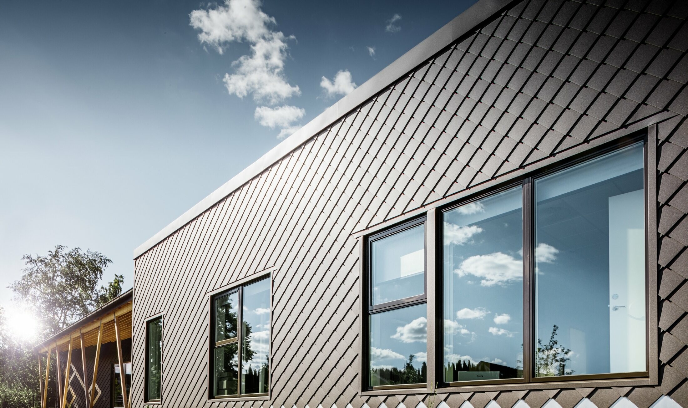 This image of a pre-school in Stockholm shows the new façade with large windows and a flat roof. The exterior façade was clad with the rhomboid façade tile 20 x 20 in brown.
