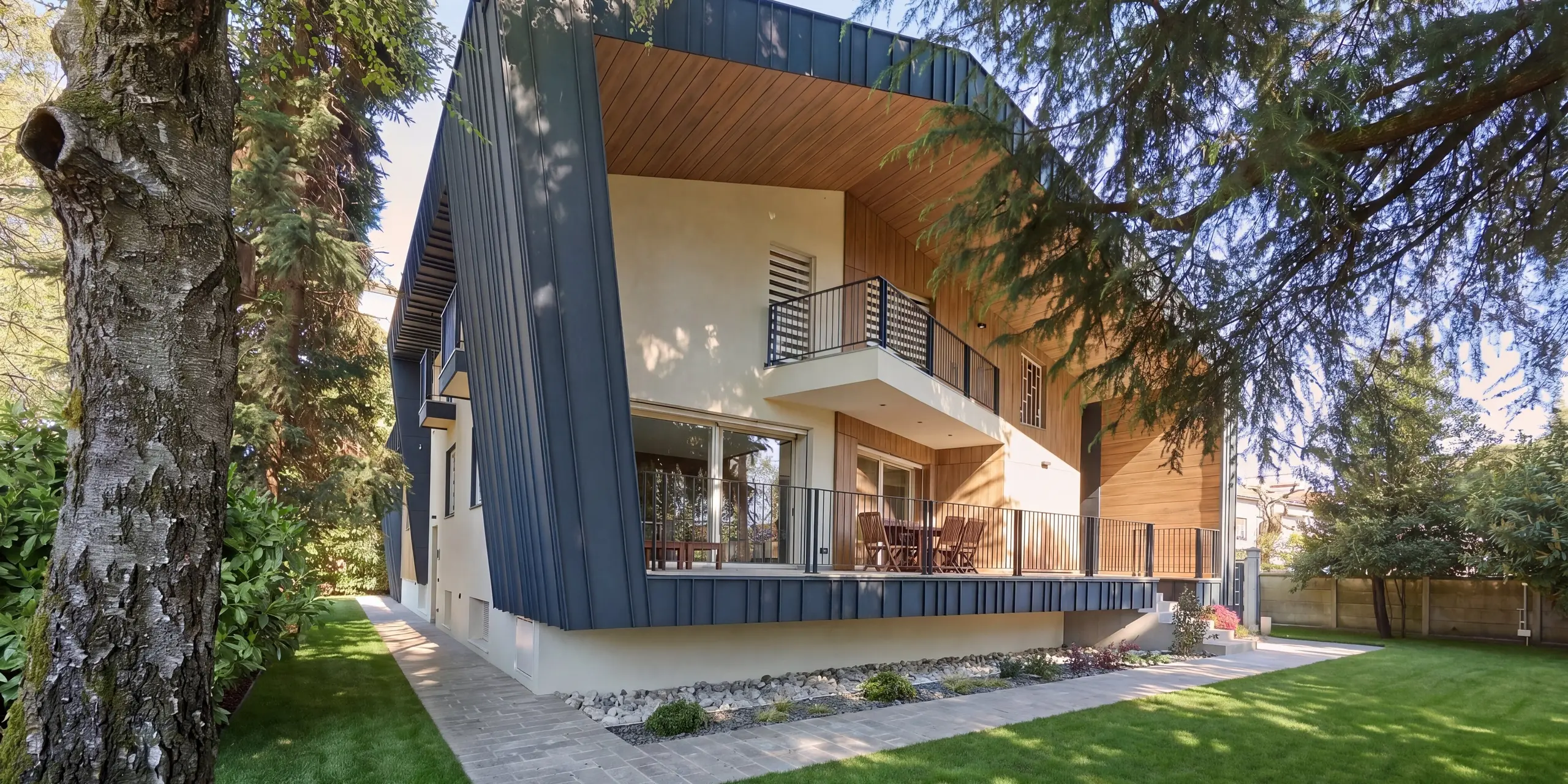 Perspektivische Gartenansicht der Villa Castellanza mit durchgängiger PREFALZ Dach- und Fassadengestaltung in P.10 Anthrazit. Die markanten Stehfalze, großzügigen Terrassen und warmen Holzakzente erzeugen eine spannende Architektursprache. Eingebettet in alten Baumbestand vereint die langlebige PREFA Aluminiumhülle modernes Design, hohe Widerstandsfähigkeit und zeitlose Eleganz auf harmonische Weise.