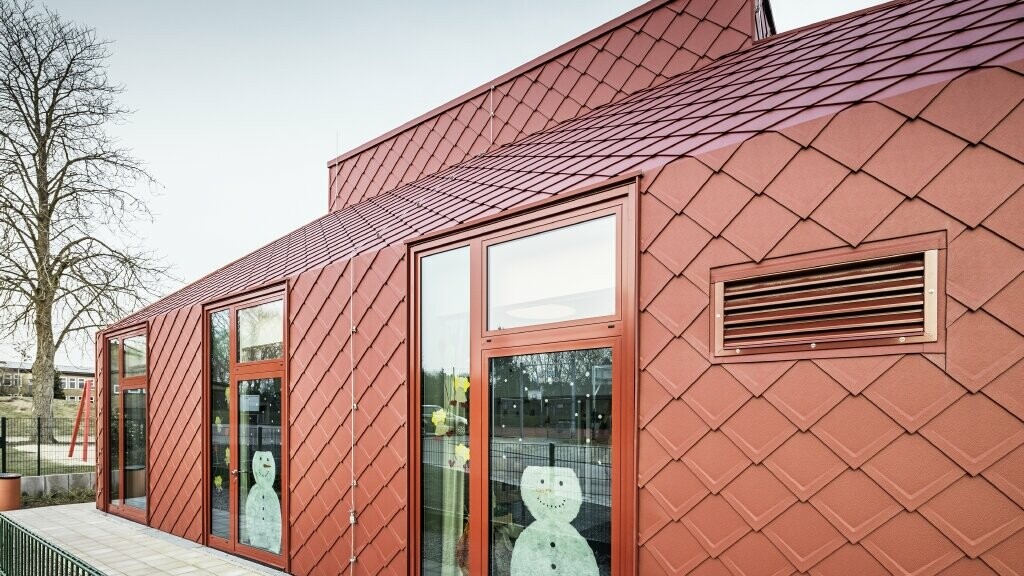 Frontal shot of the kindergarten. A snowman was glued to the windows in keeping with the season. The Hennstedt kindergarten was covered with the rhomboid roof tile 29 × 29 in oxide red.