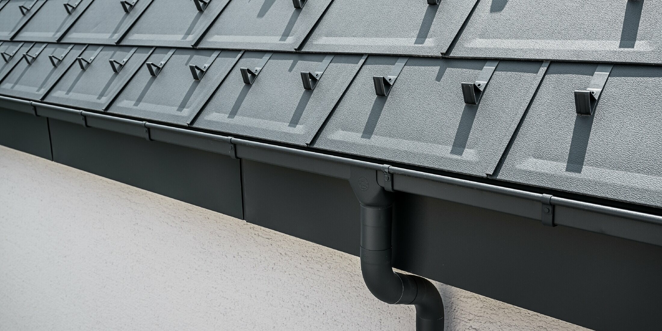 Steep roof surface covered with the roof tile R.16 with square PREFA box gutter with gutter outlet and downpipe in anthracite