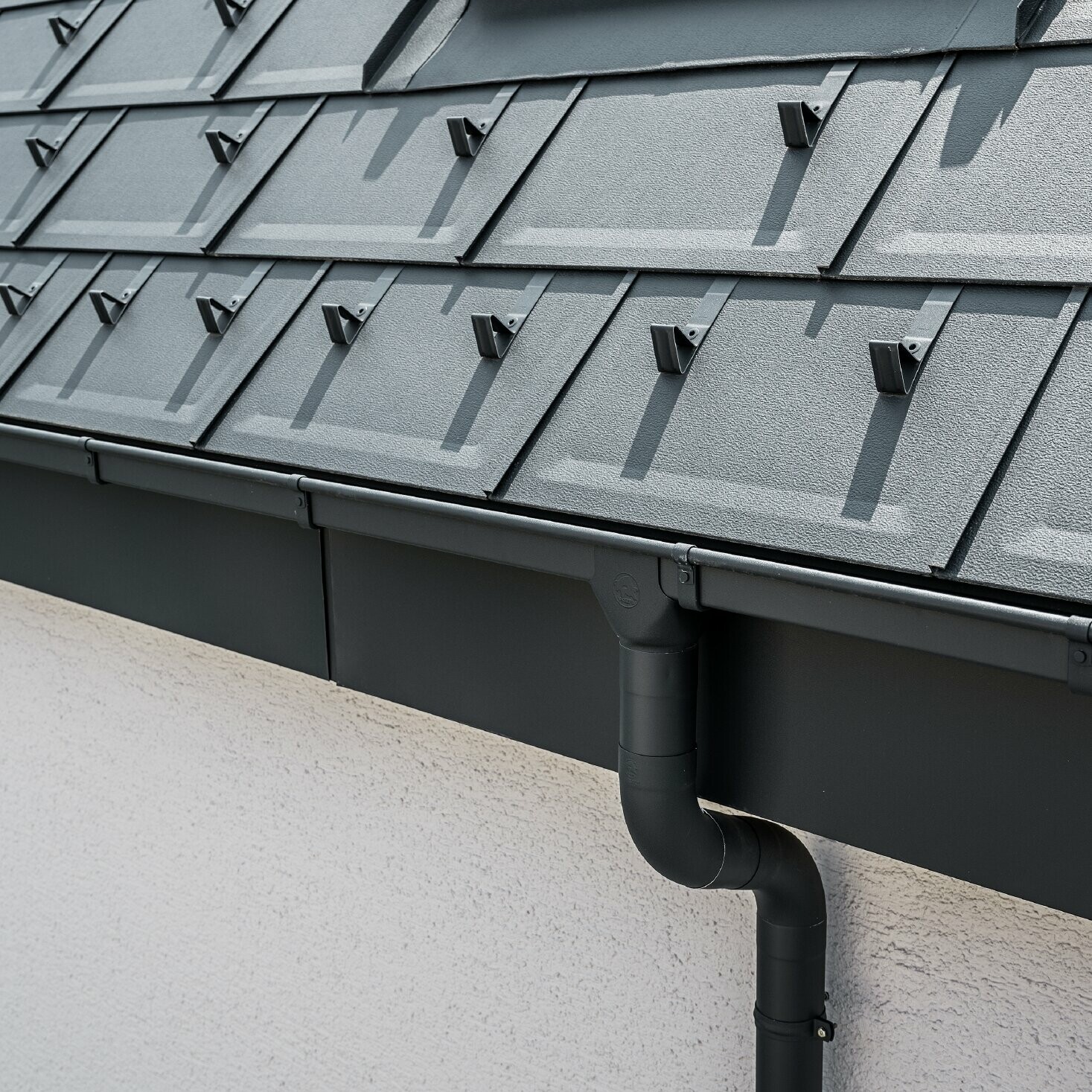 Steep roof surface covered with the roof tile R.16 with square PREFA box gutter with gutter outlet and downpipe in anthracite