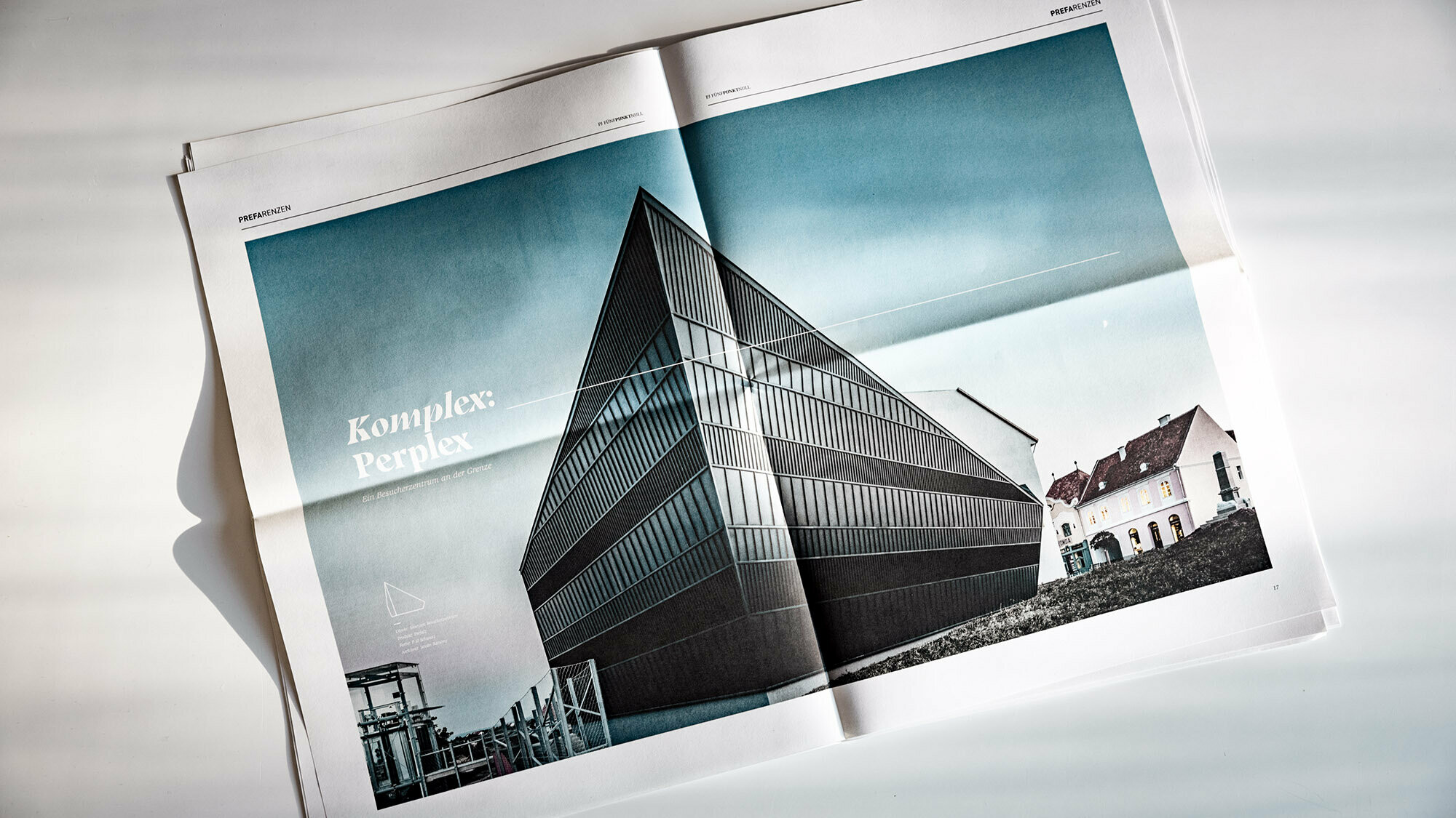 Frontal view of a tilted double page showing a black, sharp-edged building.