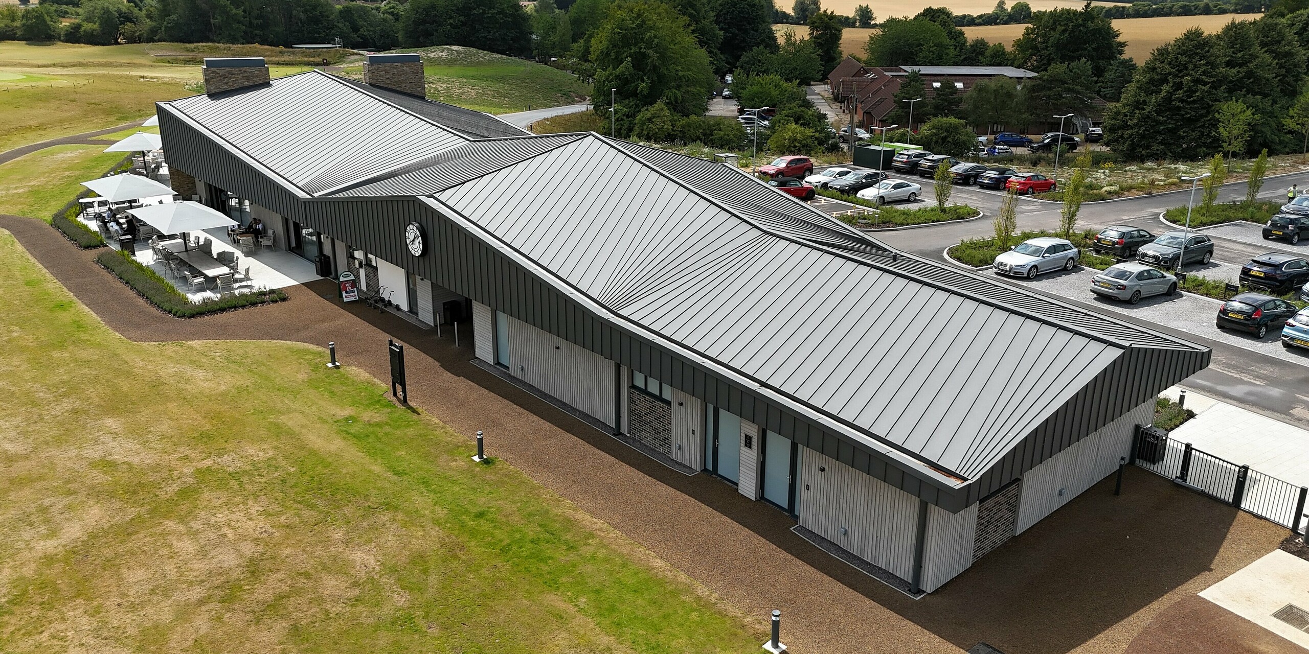 The Basingstoke Golf Club in Hampshire impresses with a modern new building, where around 1,600 m² of PREFALZ standing seam panels in P.10 dark grey characterise the roof and upper façade. The clean lines and elegant roof shape create striking accents and harmonise with the green surroundings of the golf course. The lower façade, made of wood panelling and bricks, complements the stylish design.
