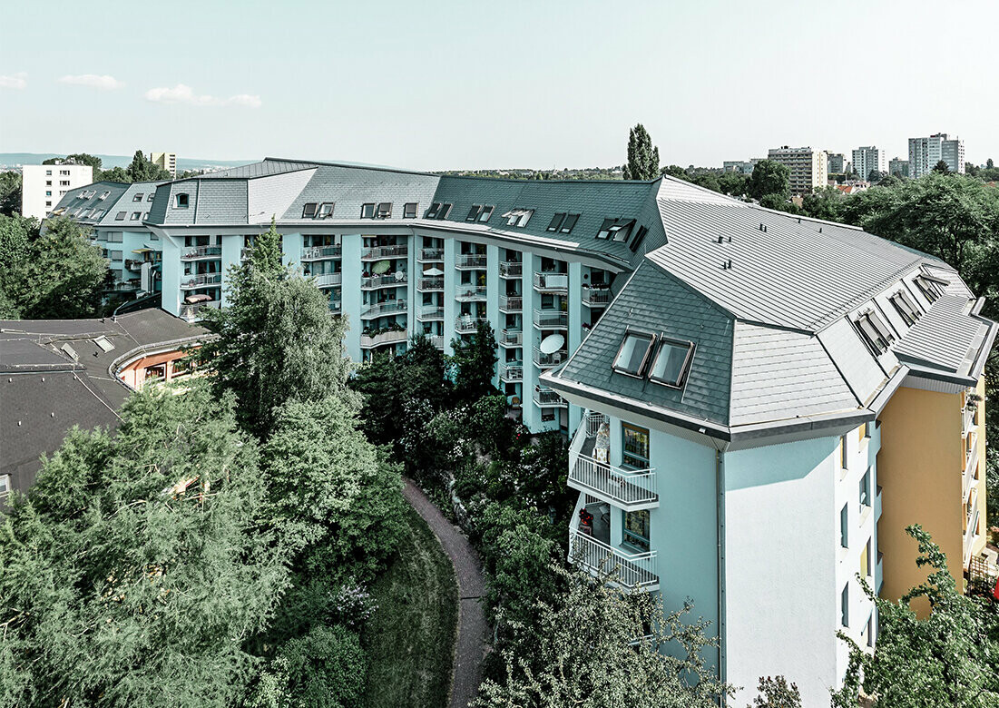 Large aged-care facility covered with the PREFA roof shingles and Prefalz in stone grey with numerous balconies.