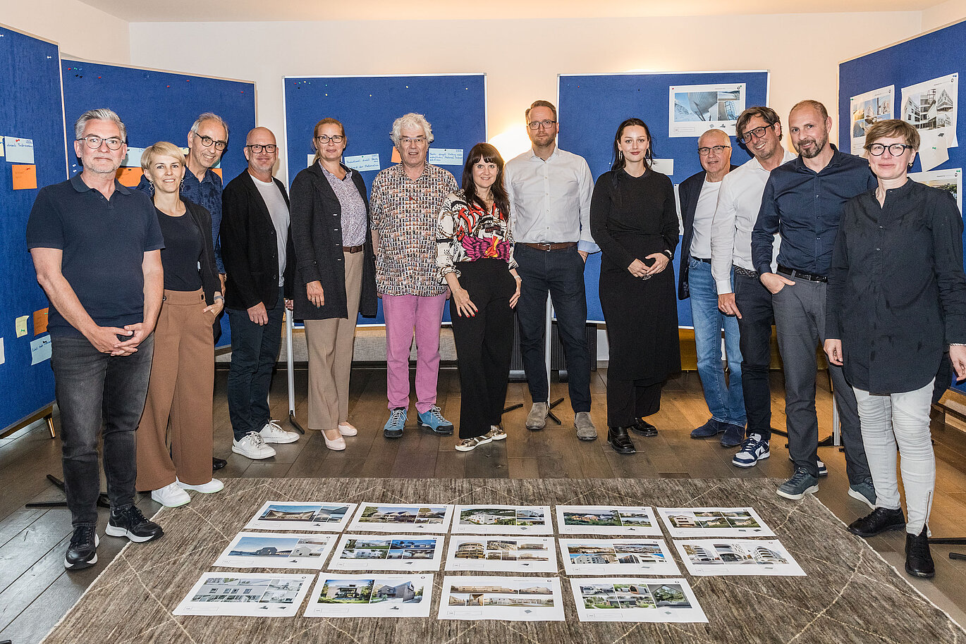 Group photo of the PREFARENZEN 2026 jury after the successful selection process in a winegrower's residence in Seewinkel, Burgenland: The interdisciplinary group of experts consisting of Dirk Lorenz (Leinert Lorenz Architekten), Veronika Roll (Marketing, PREFA Austria), Wolfgang Croce (Croce & Wir, Graz), Jürgen Jungmair (Head of International Marketing, PREFA), Judit Nemere (Managing Director, PREFA Hungary), Matthias Finkentey (Moderator), Bettina Almeida (Communications Management, PREFA), Christian Wirth (Regional Manager East, PREFA Austria), Selina Wach (Head of Discourse, Architektur Aktuell), Thomas Schlett (B3 Architekten), Sven Disser (Head of Development, Bauwerk), Falk Leinert (Leinert Lorenz Architekten) and Juliane Croce (Croce & Wir, Graz) stands in front of the final architectural projects selected for the PREFARENZEN architecture book and the 2026 calendar. The projects reflect diversity, sustainability and innovative use of PREFA materials.