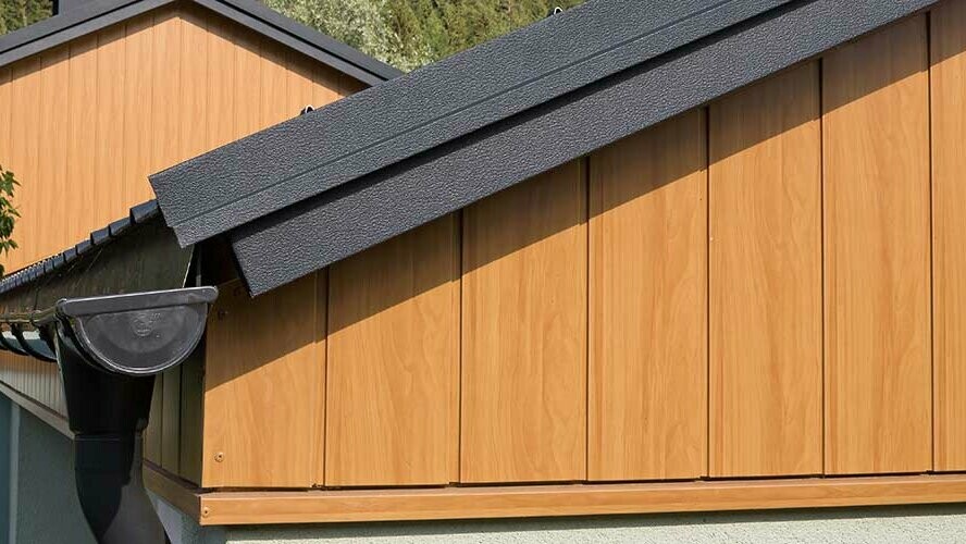 Gable cladding with aluminium sidings from PREFA in natural oak, installed vertically with a PREFA roof gutter in anthracite.