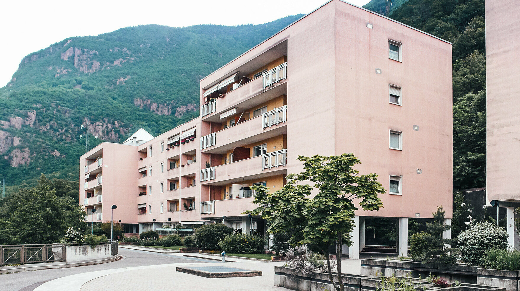 Before photo of the project on Köstenweg: a salmon-coloured, outdated concrete building.