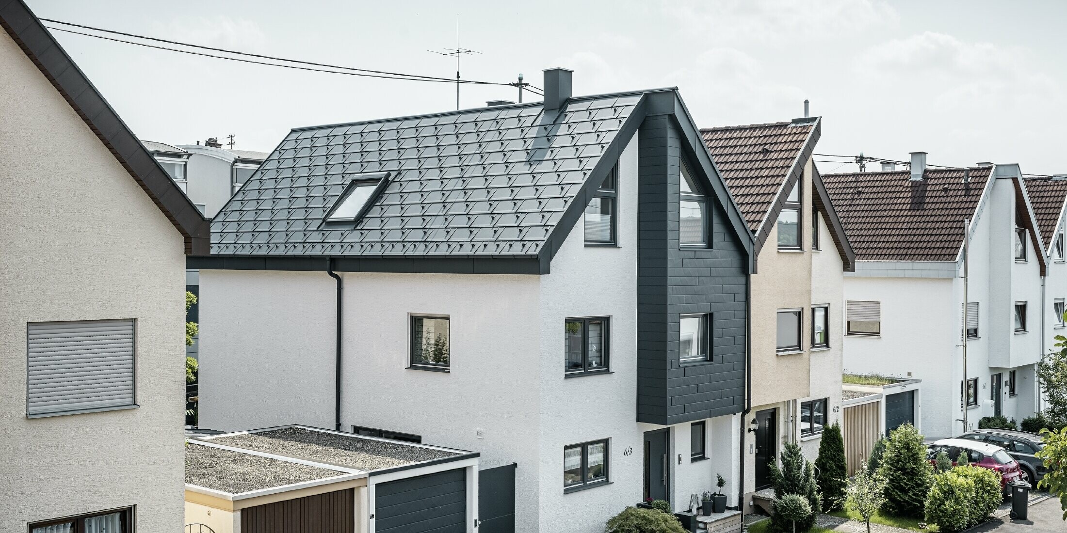 One semi-detached house has already been renovated, with a fresh white plaster façade, combined with a PREFA siding.X façade in anthracite. The roof was covered with PREFA roof tile R.16. The roof is drained via the square box gutter and the PREFA downpipe.