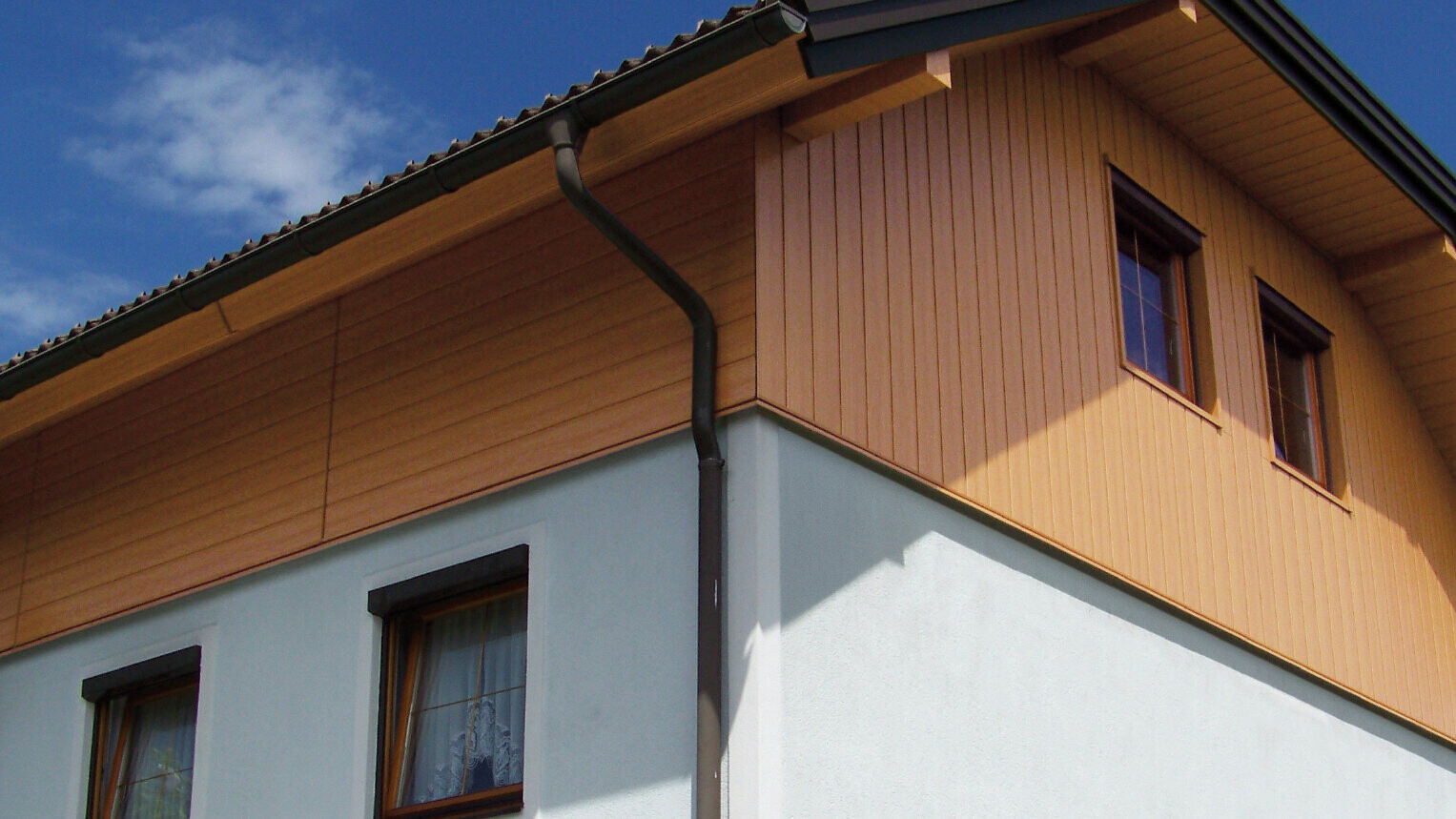 Large detached house with half-hipped roof and gable cladding using PREFA sidings in wood effect (natural oak colour)