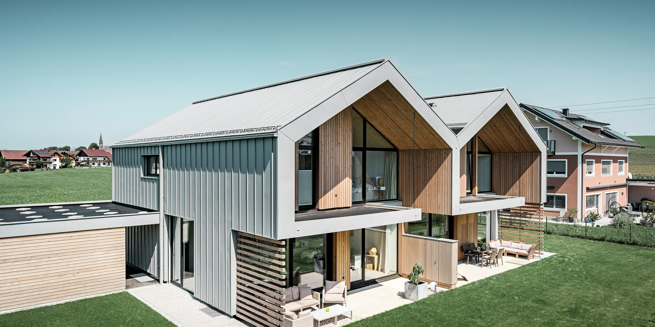 Modern semi-detached houses with PREFALZ (standing seam) building shell, roof and façade are clad with PREFALZ standing seam in patina grey incl. square downpipe