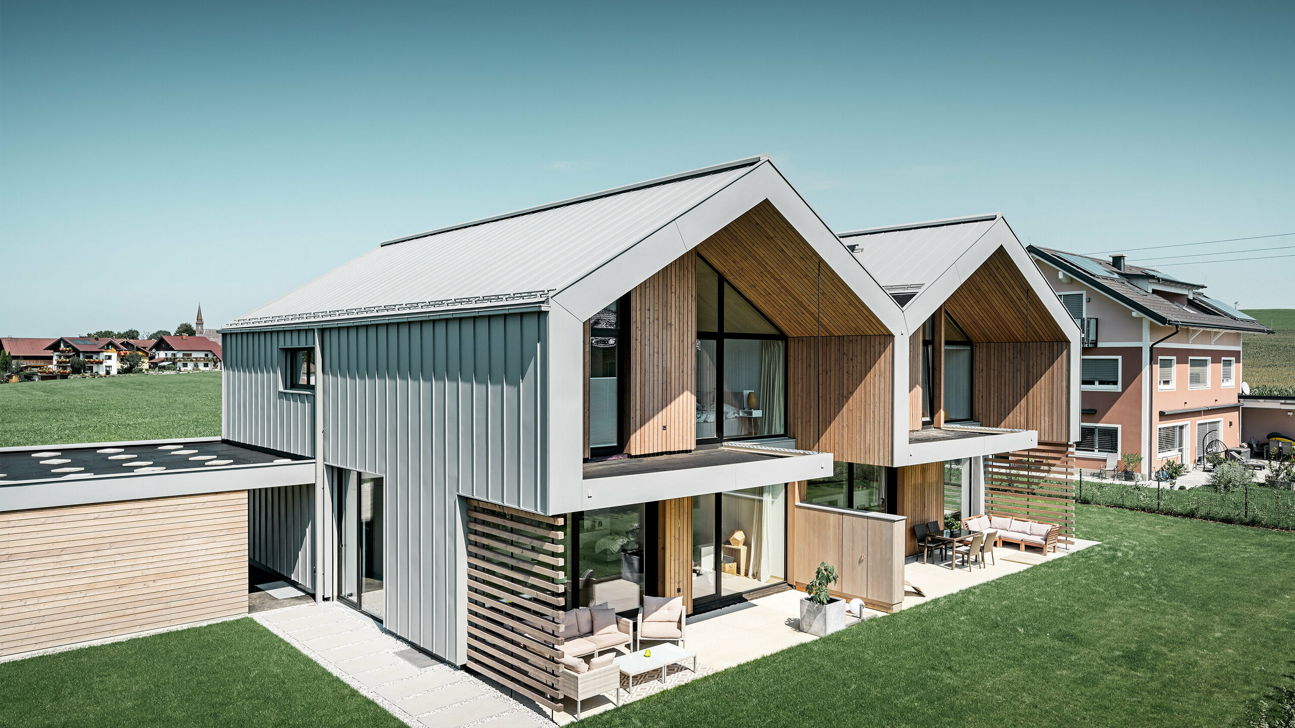 Modern semi-detached houses with PREFALZ building shell, roof and façade are clad with PREFALZ in patina grey incl. square downpipe