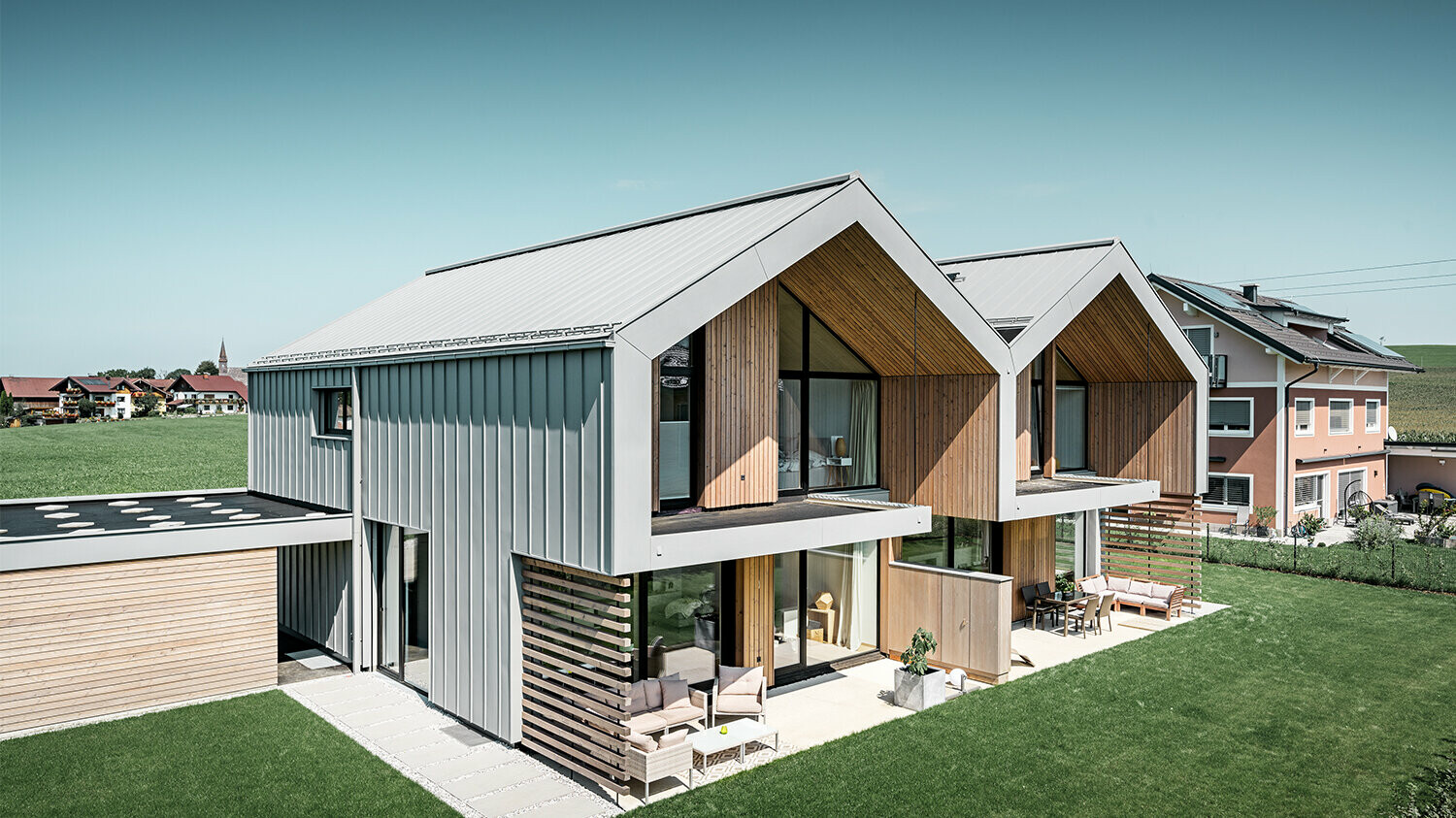 Modern semi-detached houses with PREFALZ building shell, roof and façade are clad with PREFALZ in patina grey incl. square downpipe