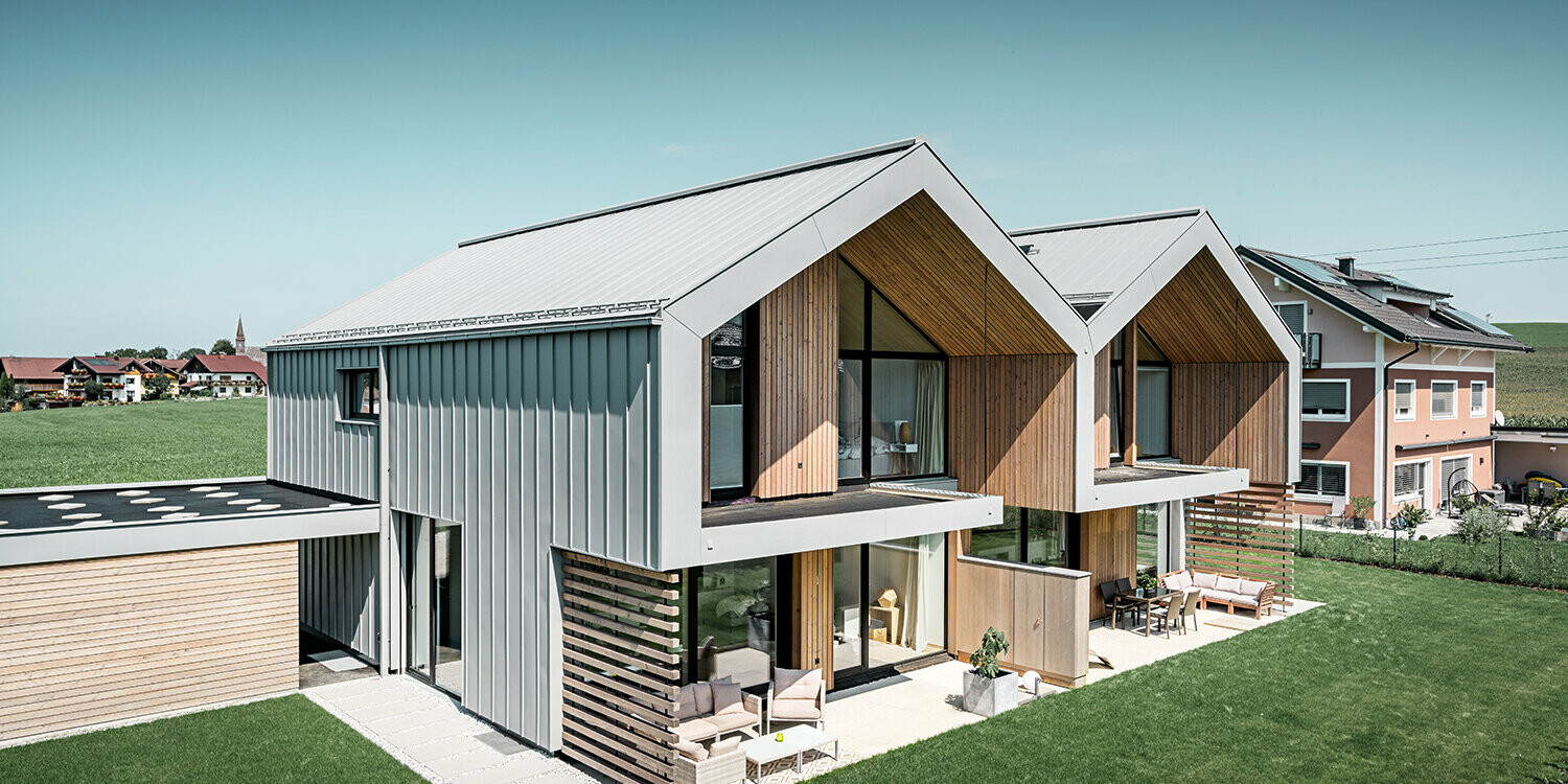 Modern semi-detached houses with PREFALZ building shell, roof and façade are clad with PREFALZ in patina grey incl. square downpipe