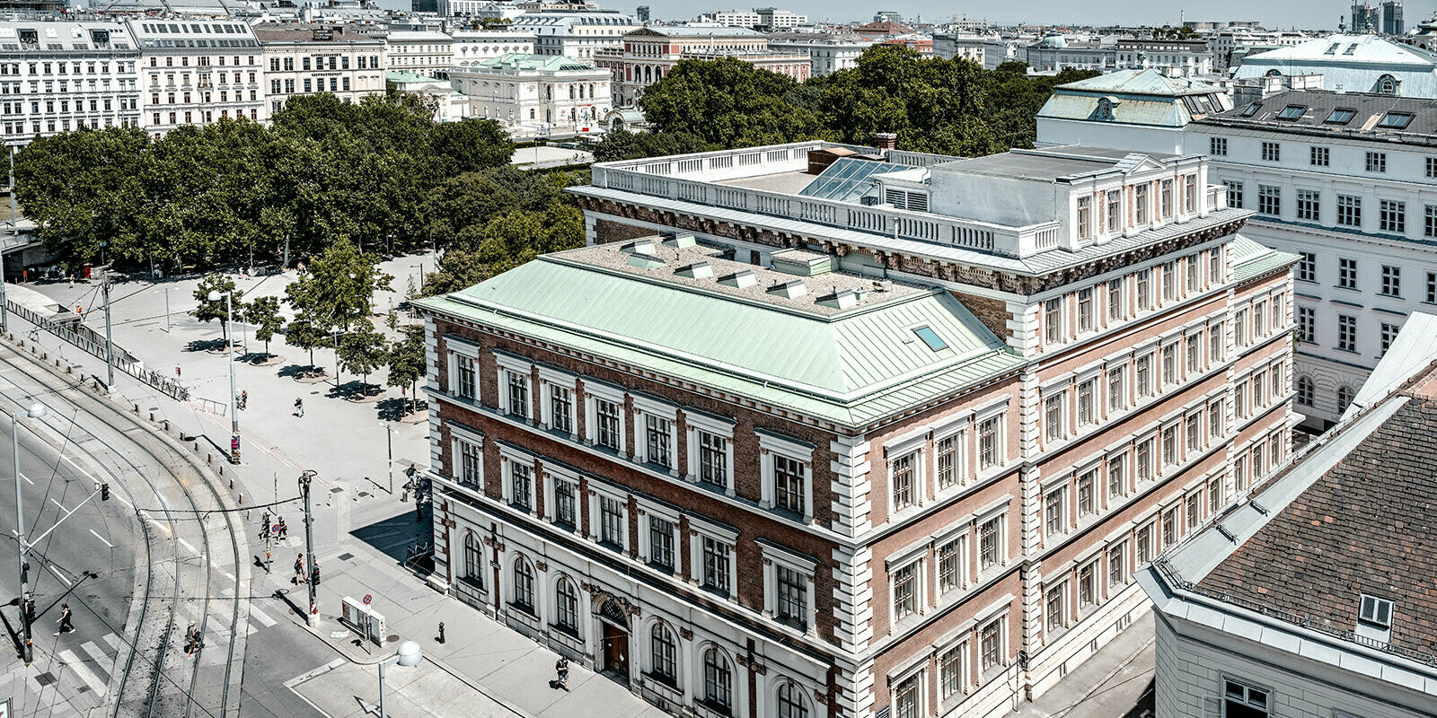 View of the protestant elementary school at Karlsplatz, Vienna. It is surrounded by buildings and trees.