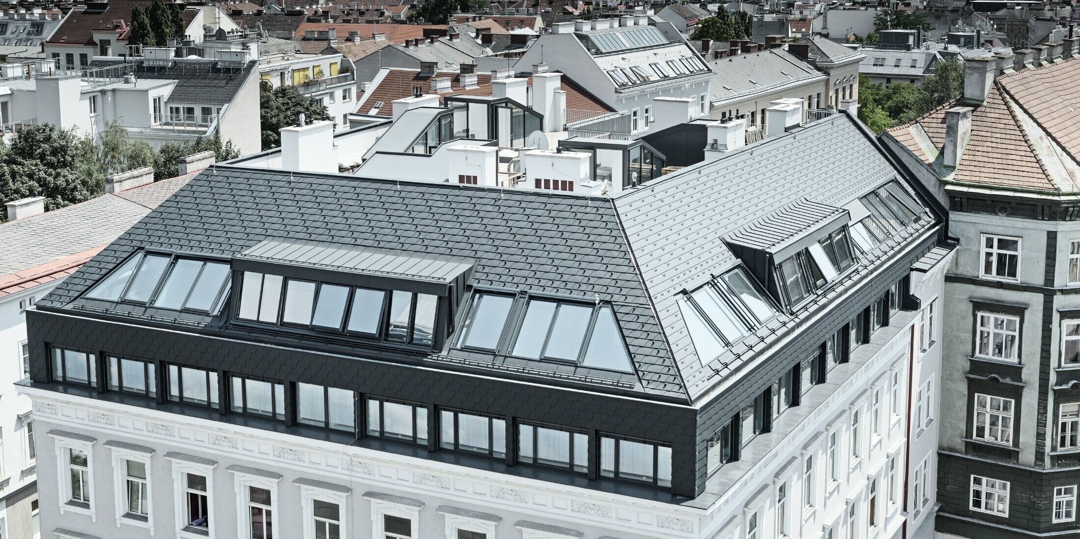 Vogelperspektive einer Wohnausanlage in der Wiener Mariahilferstraße - ausgebautes Dachgeschoss mit der PREFA Dachschindel in Anthrazit.