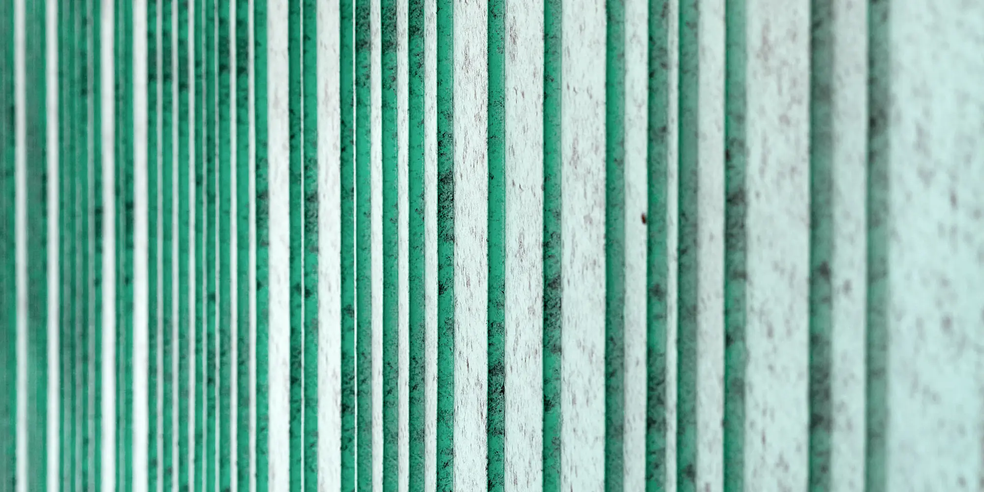 Detailed view of the patina green aluminium façade, rhythmized with differently wide trays. The colour creates a speckled appearance.