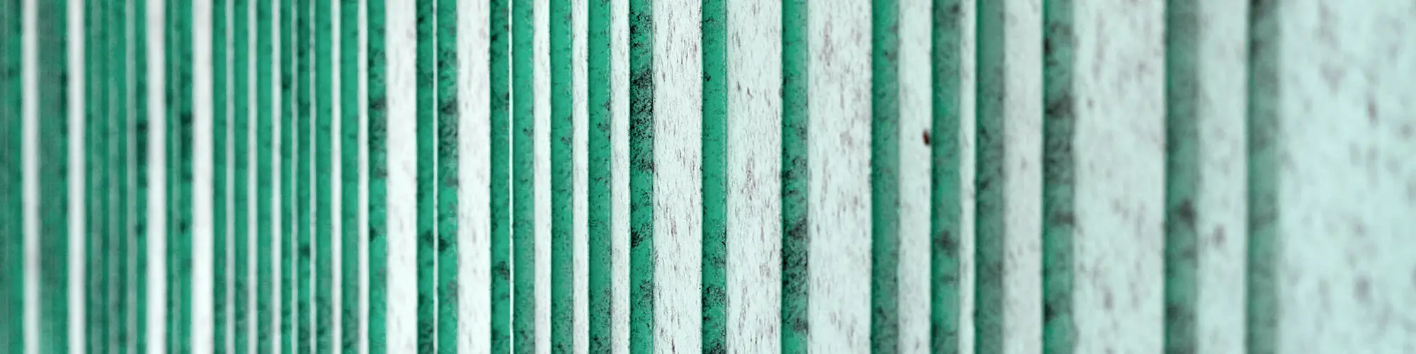 Detailed view of the patina green aluminium façade, rhythmized with differently wide trays. The colour creates a speckled appearance.