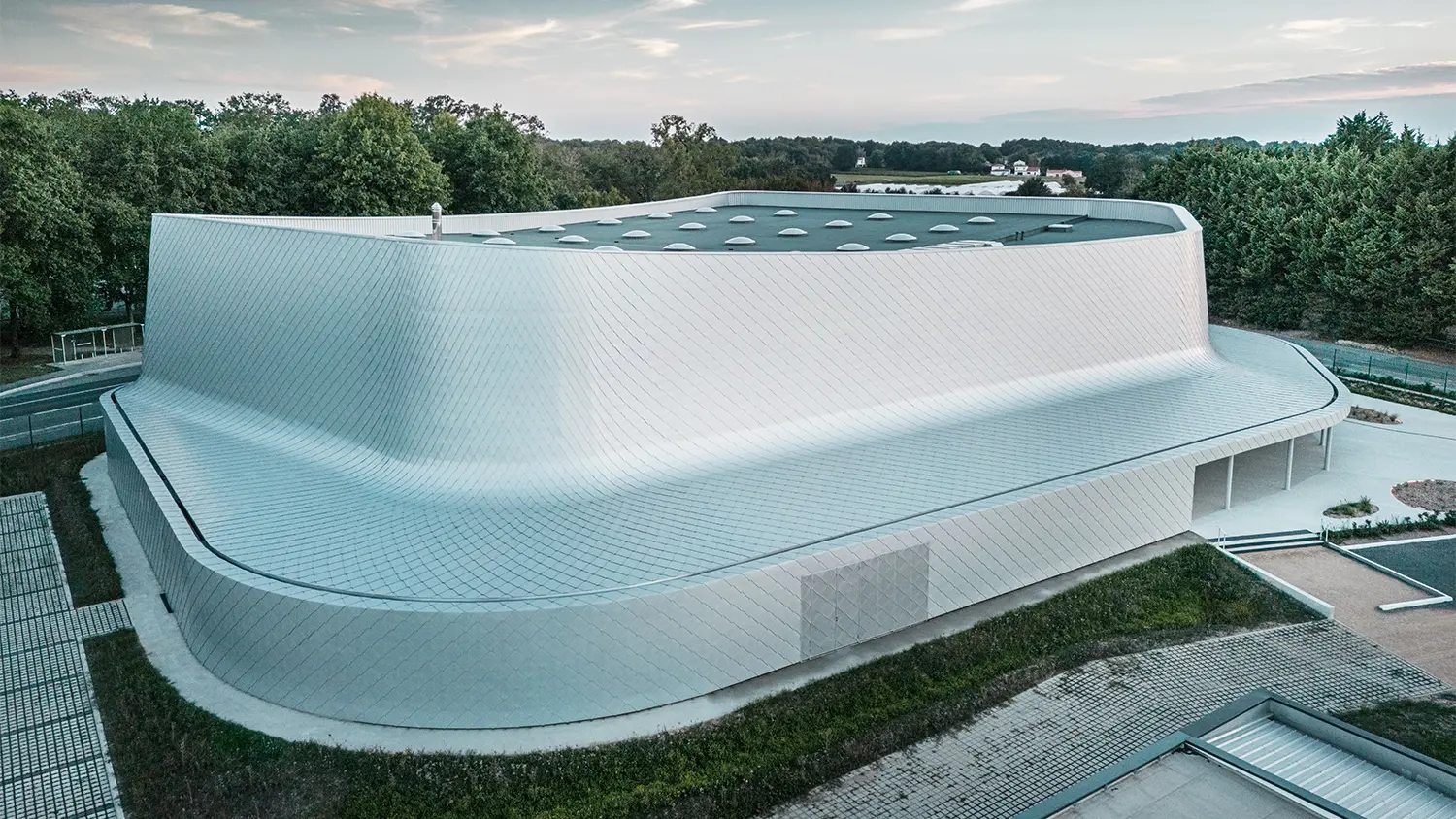 Lateral bird eye's view of the building with its immediate surroundings and a view of the roof's surface.