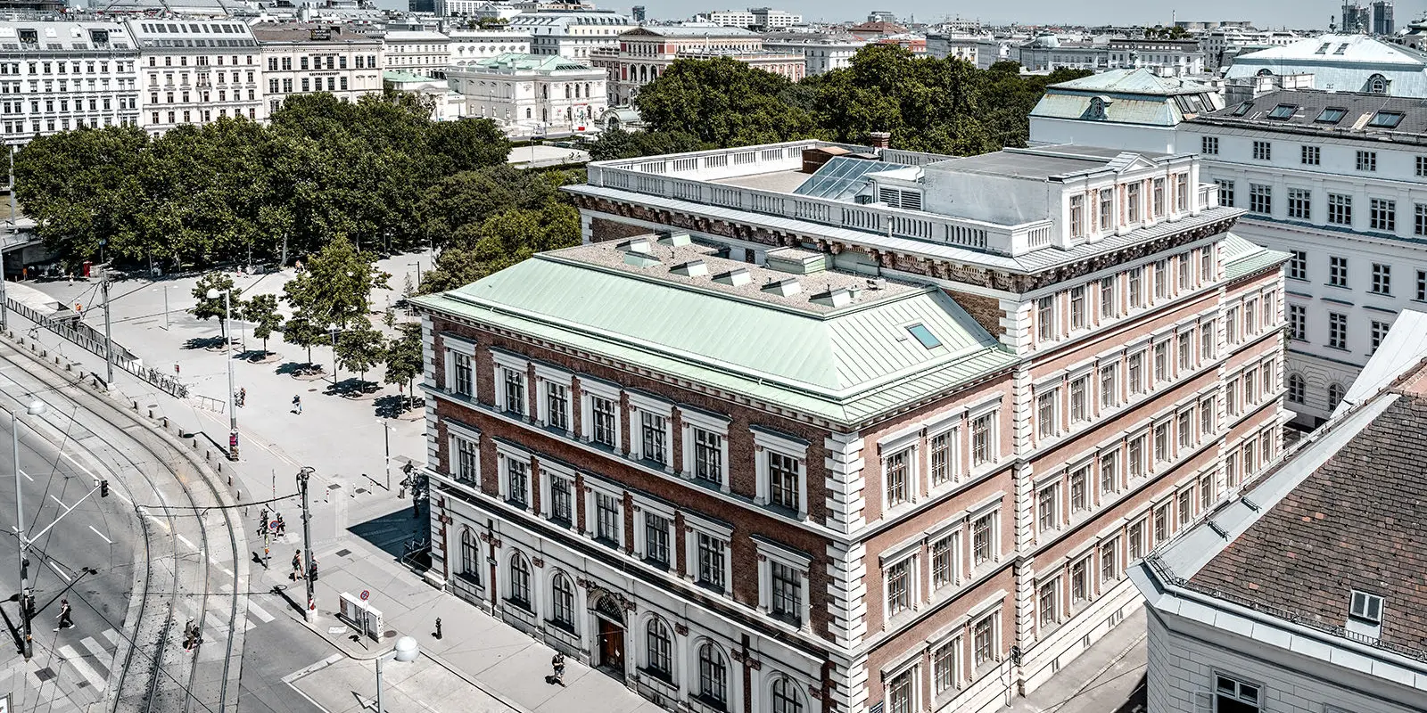 View of the protestant elementary school at Karlsplatz, Vienna. It is surrounded by buildings and trees.