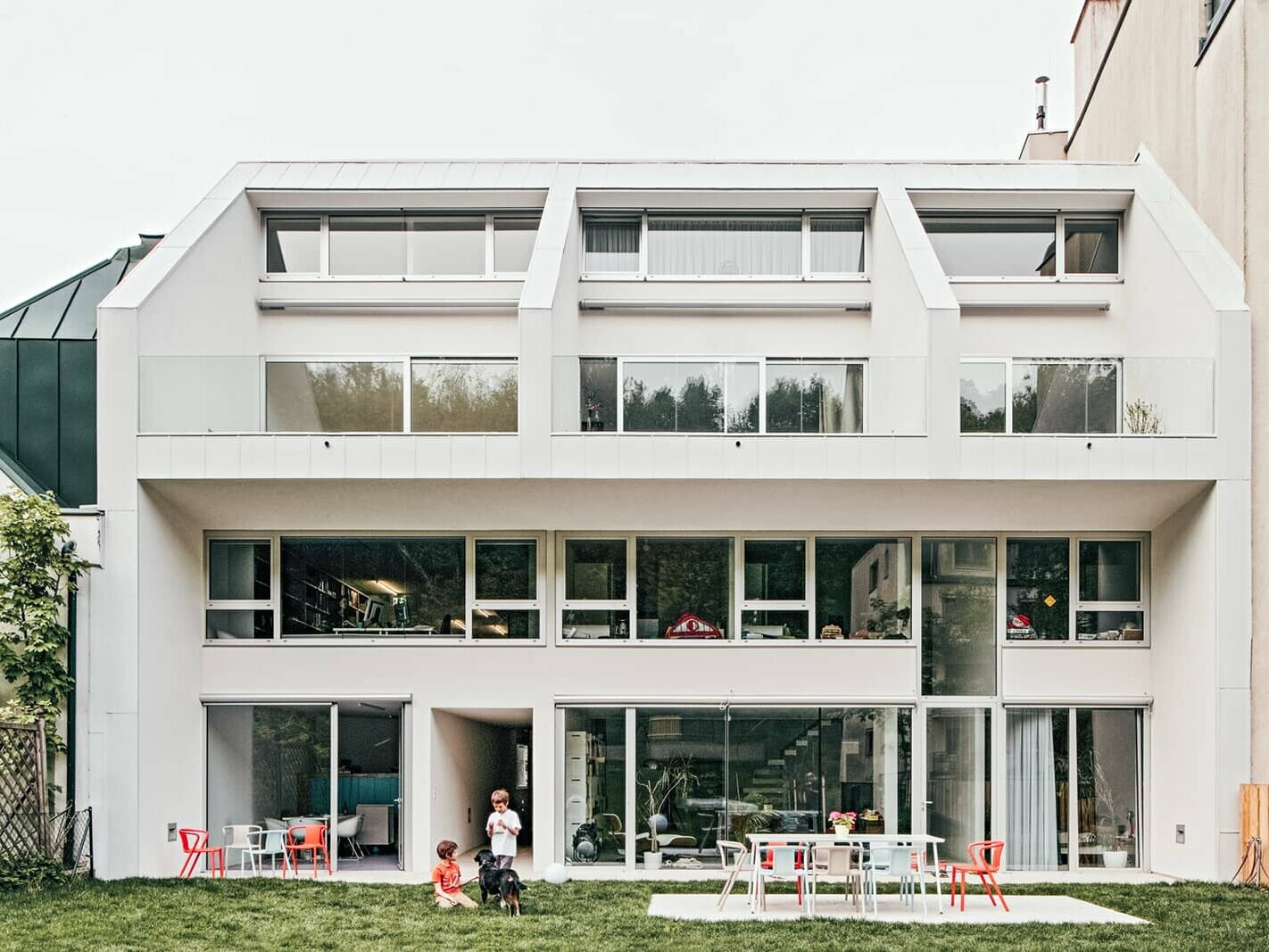 Front view of the superblock office by daylight. Two kids are playing in the garden with a dog.