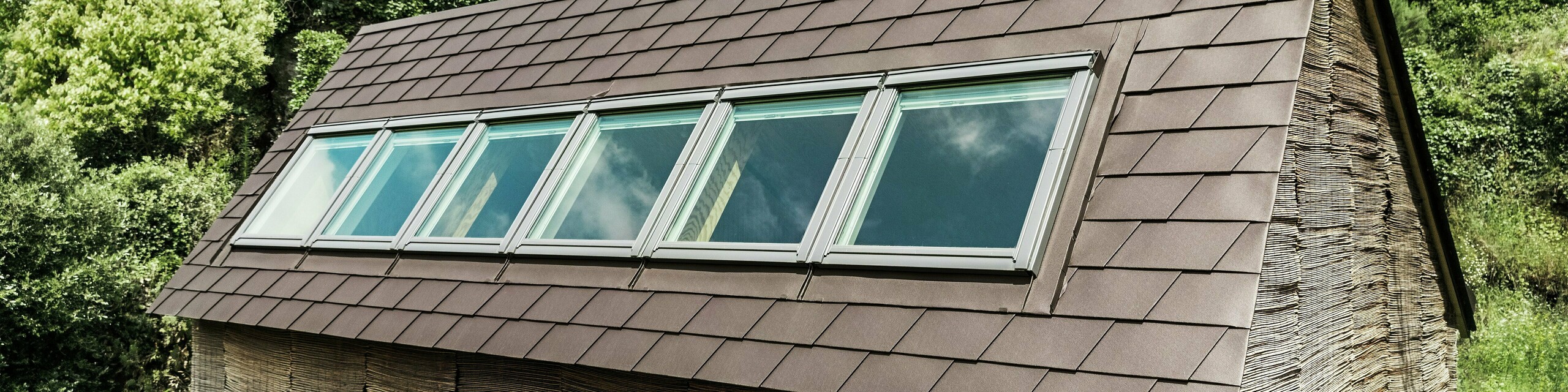 PREFA Dachschindeln in P.10 Nussbraun auf modernem Hausdach mit Dachfenstern – langlebige Aluminiumdachlösung für energieeffiziente und stilvolle Dachgestaltung.