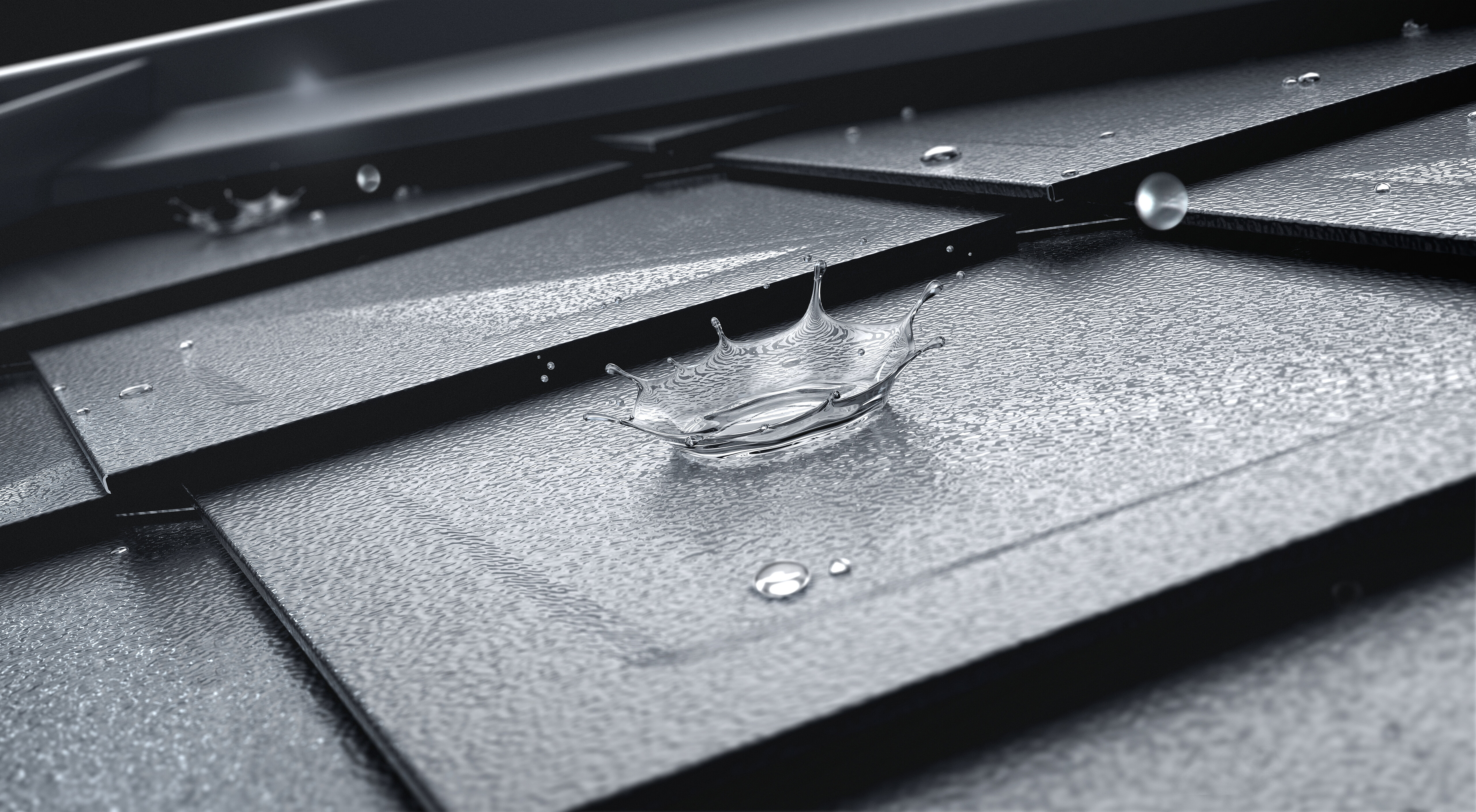 Close-up of the PREFA rhomboid roof tile with water drops on the surface. The surface of the roof panel is stucco and the colour is anthracite. 