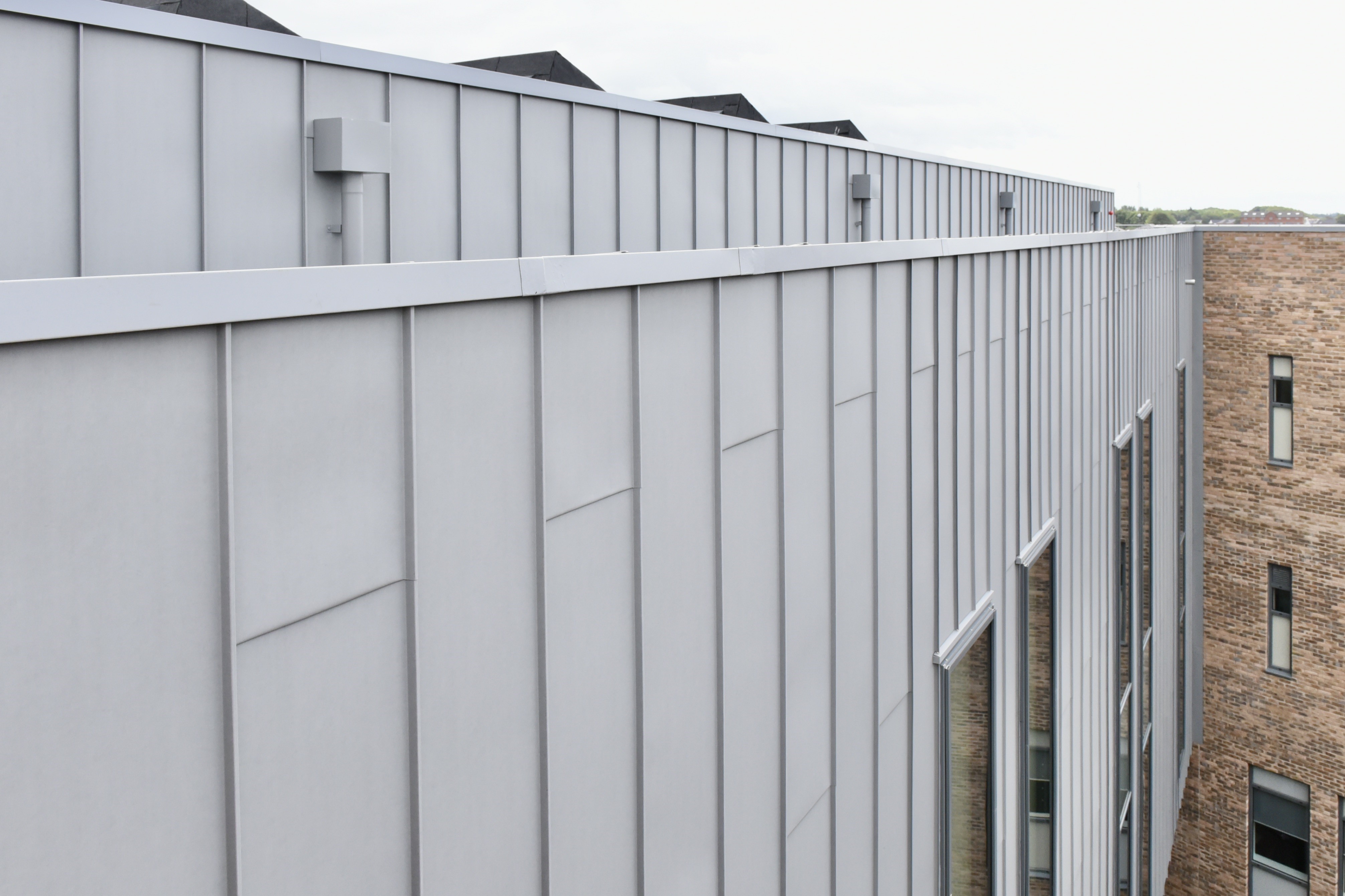 Detailed view of the PREFALZ aluminium facade in patina grey at the Regional College North, UK. The clear lines and matt appearance of the standing seam cladding emphasise the high-quality workmanship and timeless design.